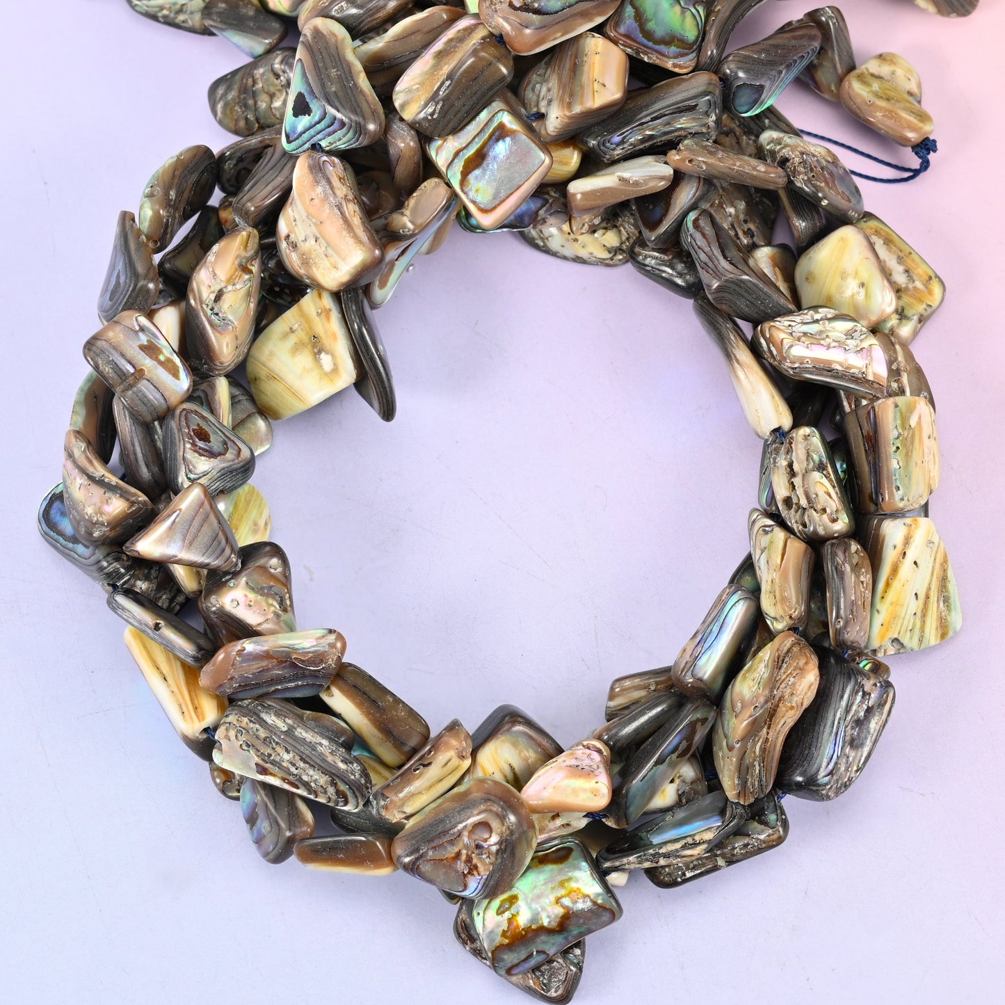 Abalone shell freeform bead strands coiled, showing the larger one-side-polished pieces