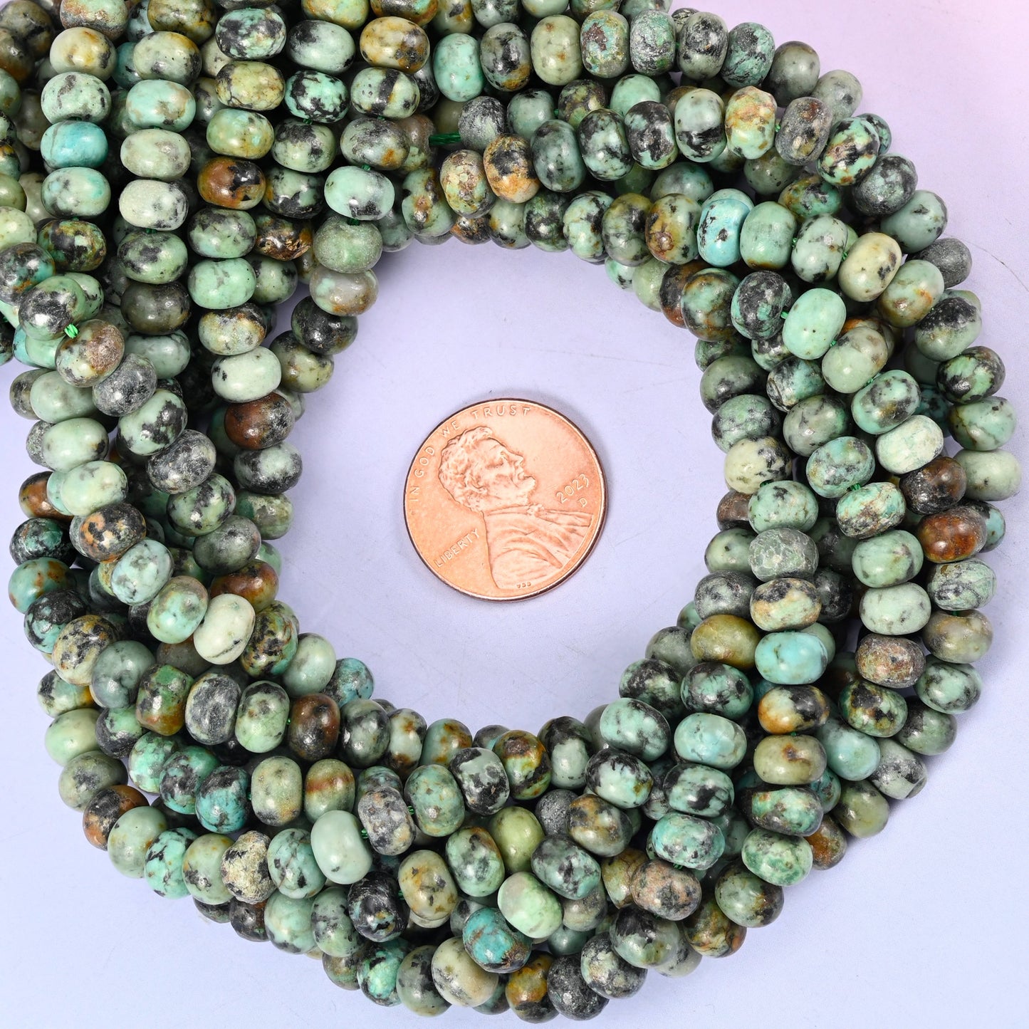 Natural African Howlite smooth rondelle bead strands coiled around a US penny for size reference