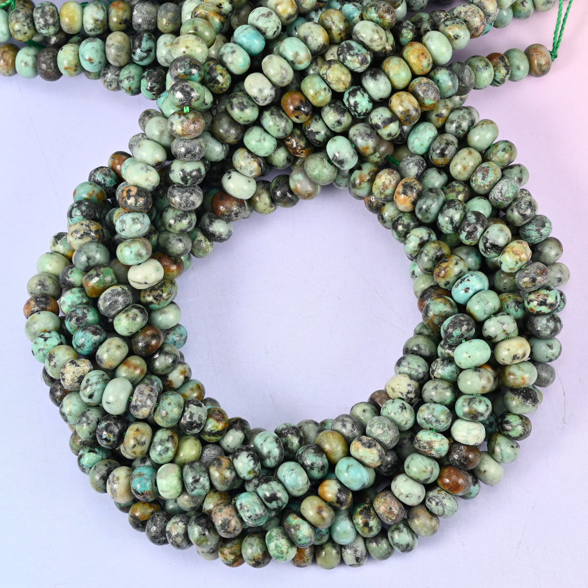 Natural African Howlite smooth rondelle beads, close view of the coiled strands showing seafoam green with black matrix veining