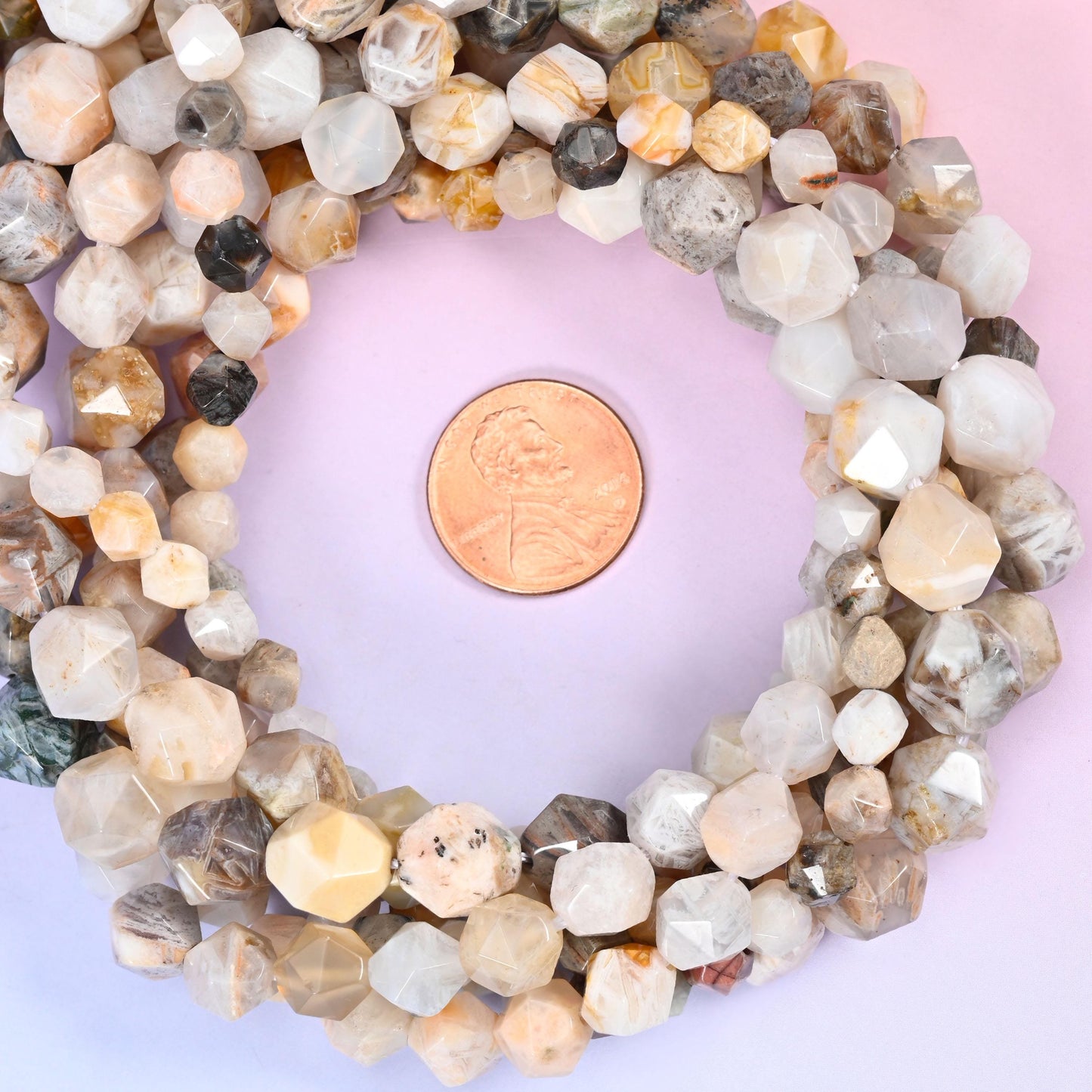 Bamboo agate faceted diamond star cut bead strands coiled around a US penny for size reference