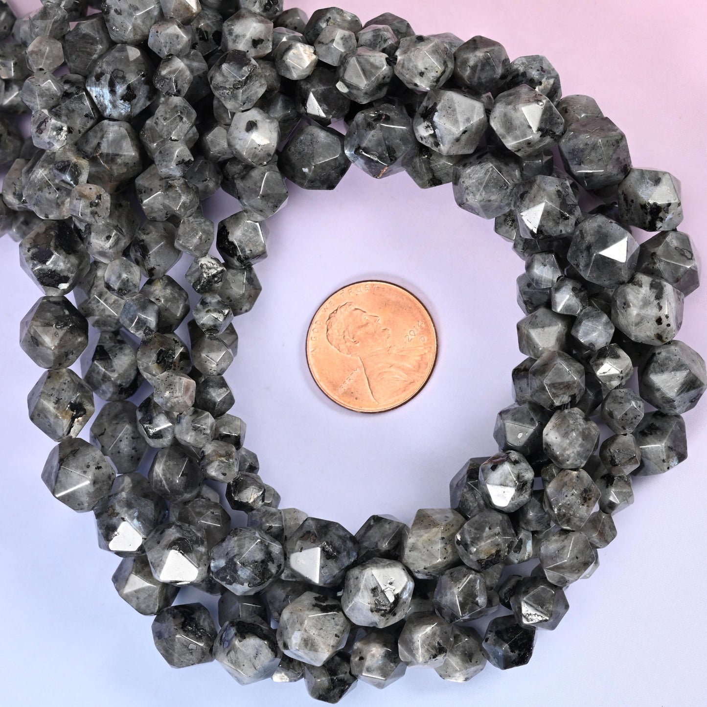 Black Labradorite faceted diamond star cut bead strands coiled around a US penny for size reference