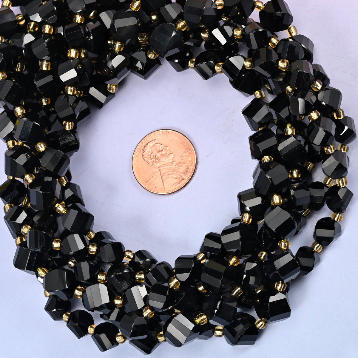 Black Onyx faceted spiral twist bead strands coiled around a US penny for size reference