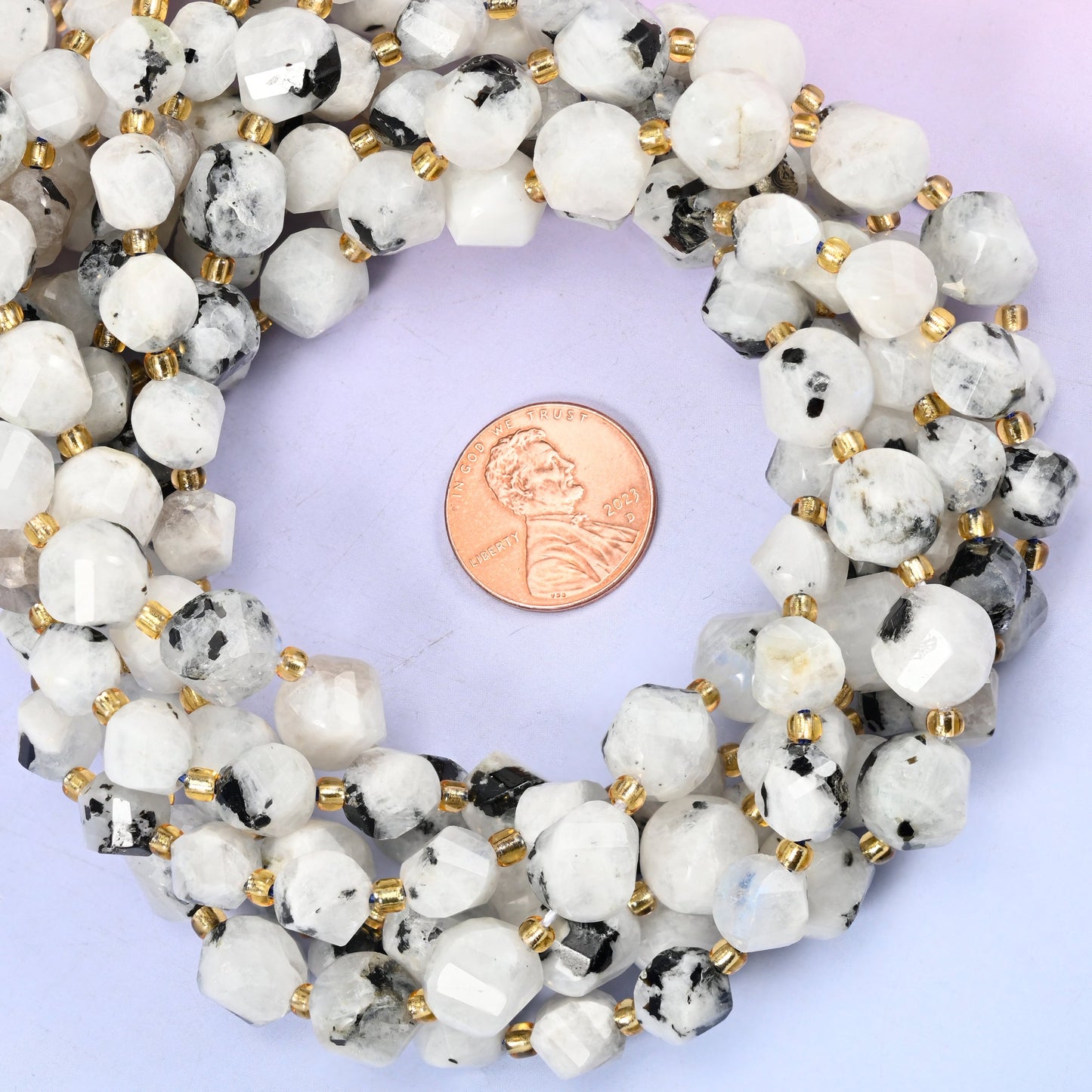 Blue Moonstone faceted spiral twist bead strands coiled around a US penny for size reference