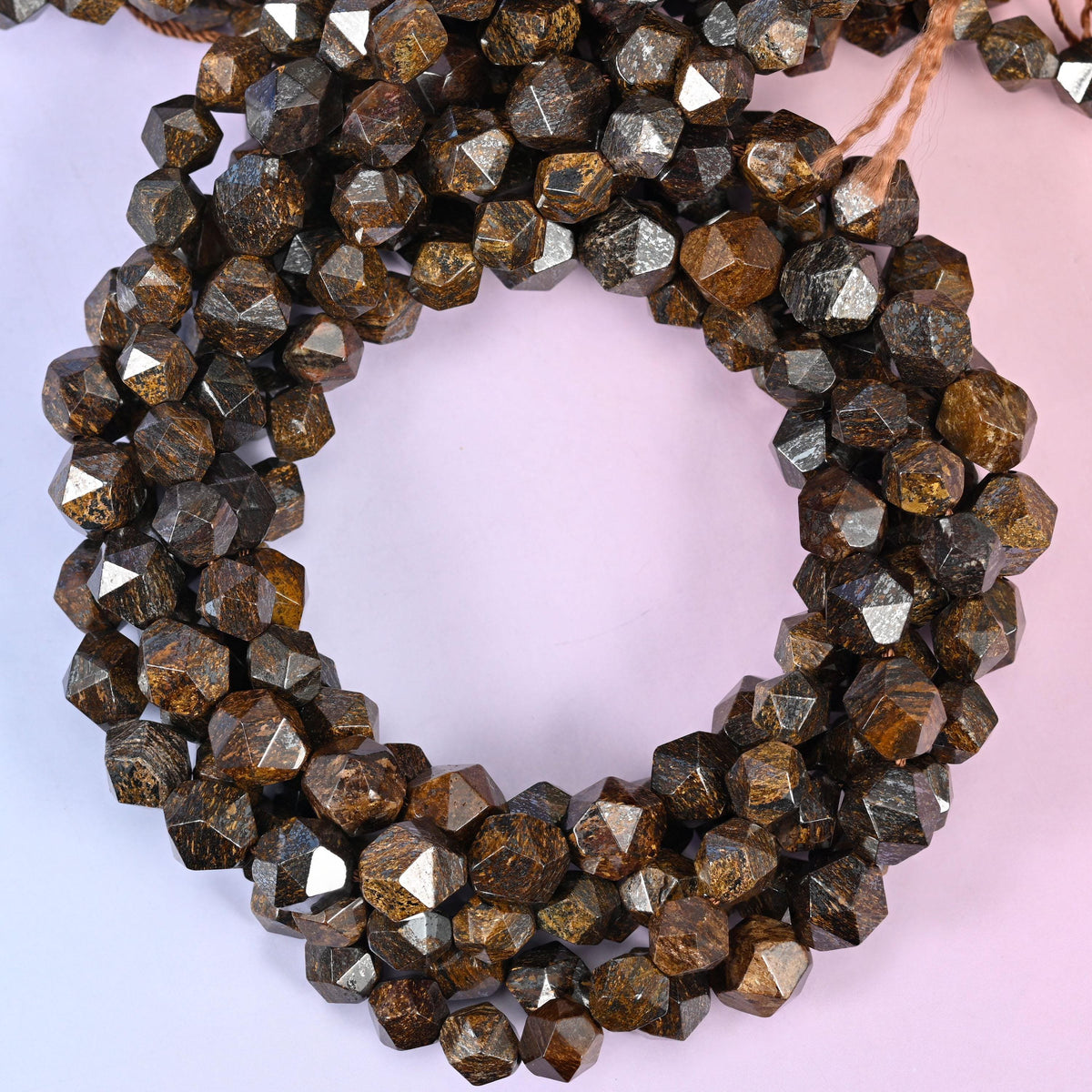Bronzite faceted diamond star cut beads, close view of the coiled strands showing bronze brown with metallic sheen