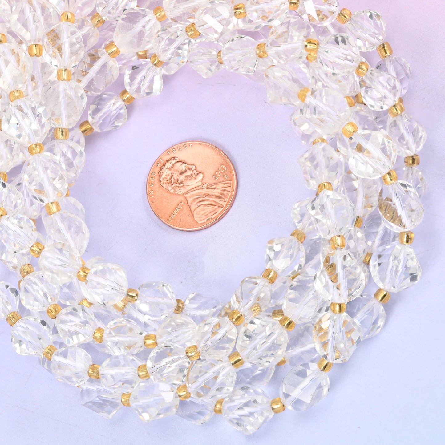 Clear Quartz faceted spiral twist bead strands coiled around a US penny for size reference