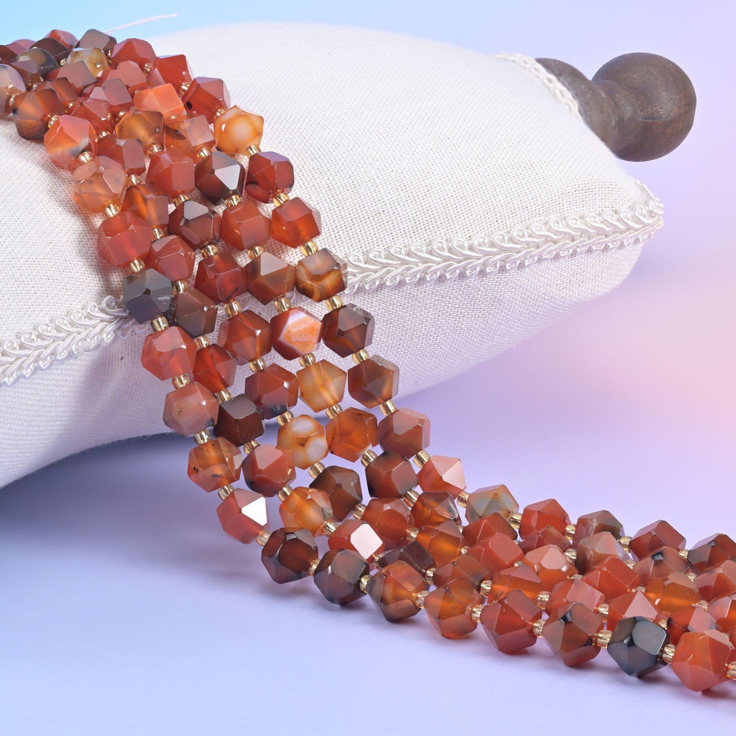 Faceted 8 sided diamond rhombus beads on a white display cushion, 10mm mixed stone