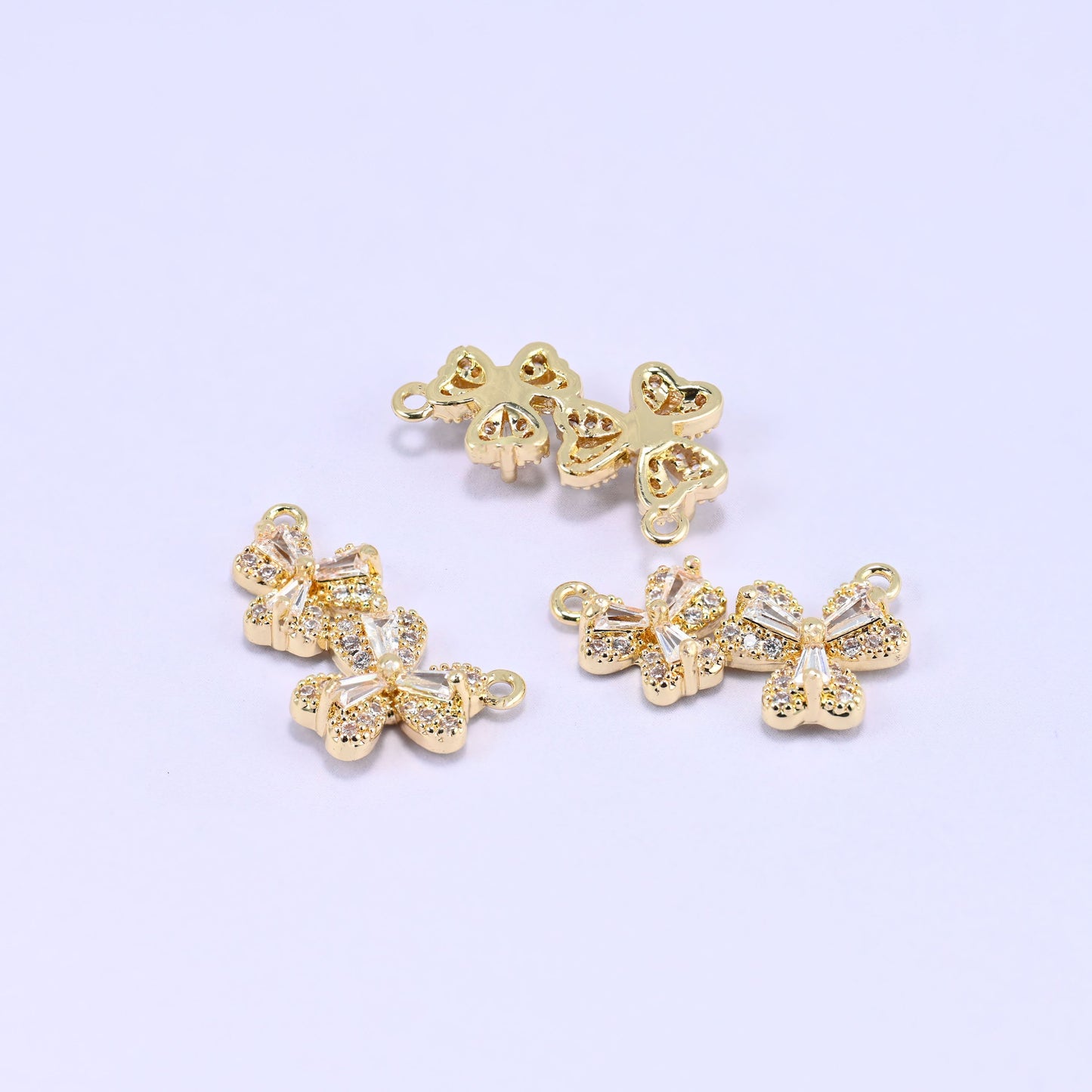 Three gold-plated flower zircon connector pendants on a lilac background