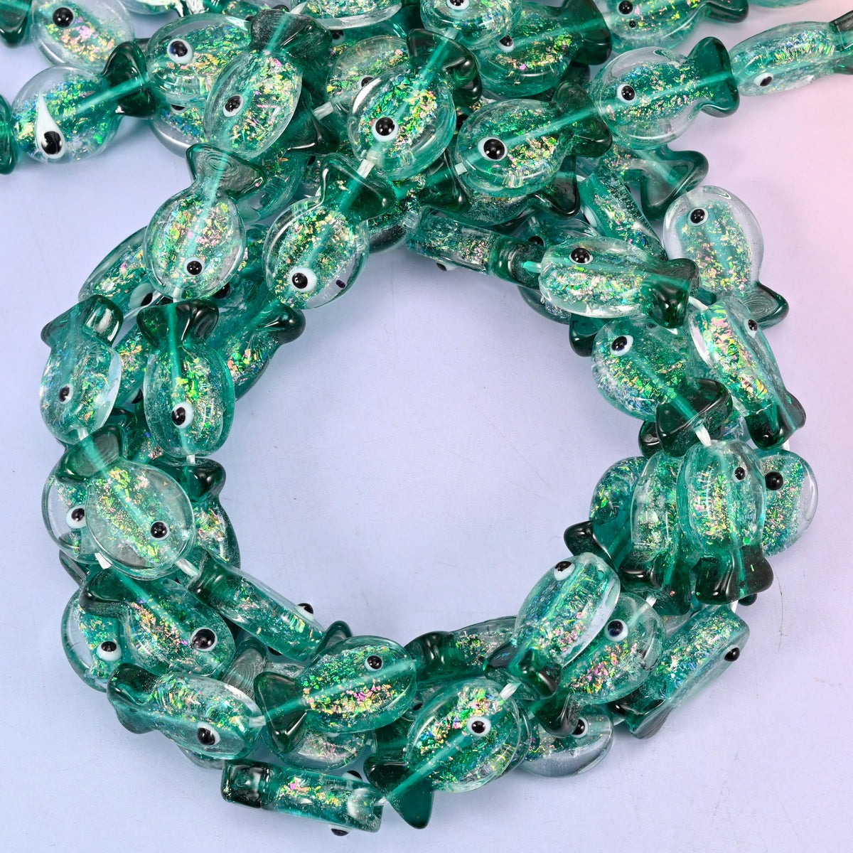 Iridescent Green Fish glass beads, close view of the coiled strands in deep green with gold glitter inclusions