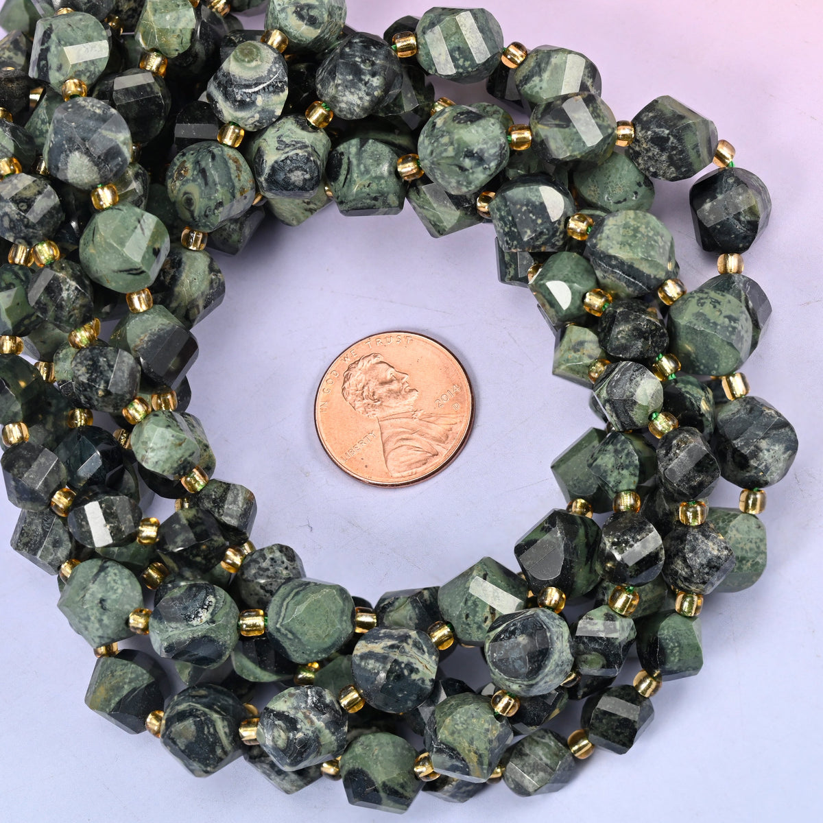 Kambaba Jasper faceted spiral twist bead strands coiled around a US penny for size reference