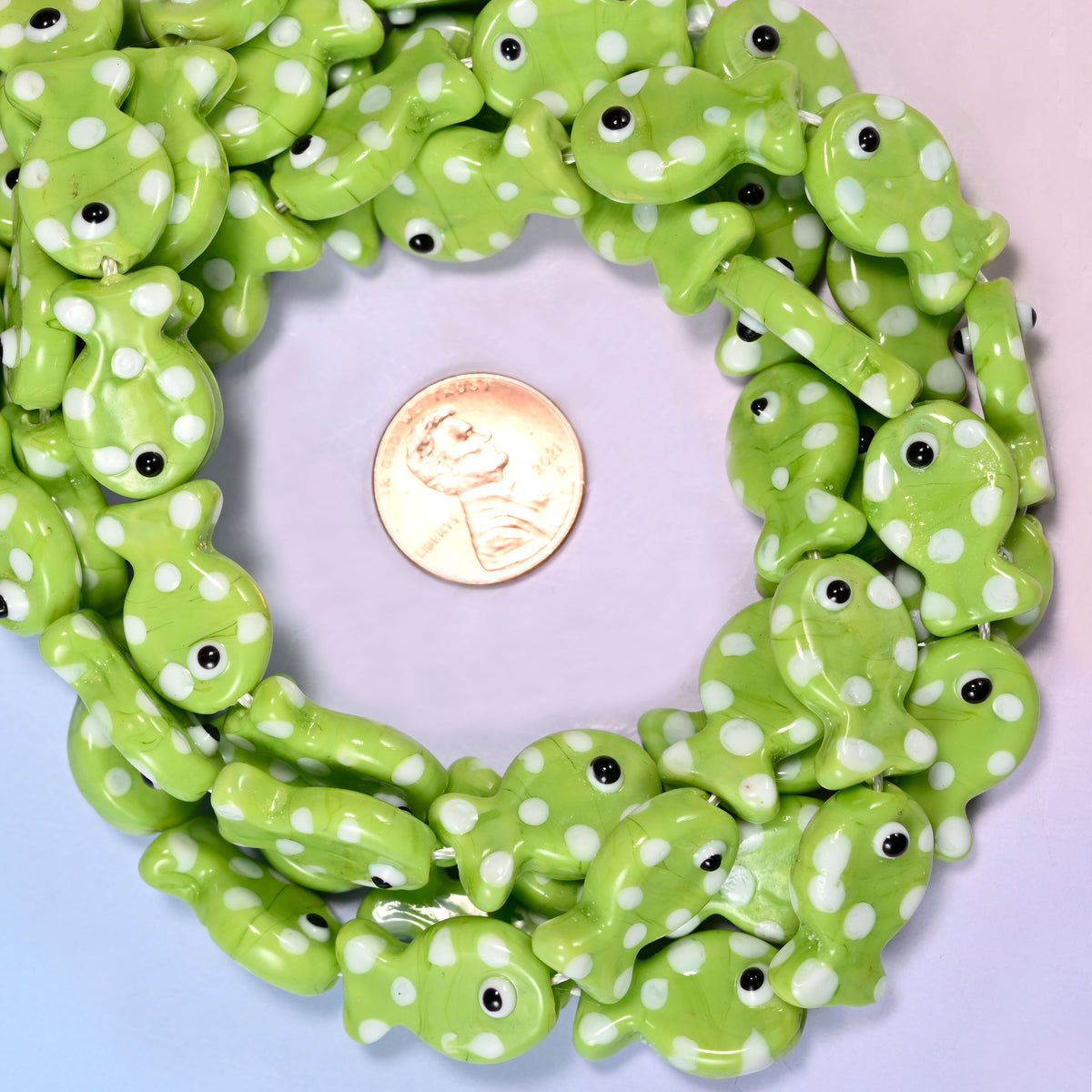 Lime Green with White Dot Fish glass bead strands coiled around a US penny for size reference