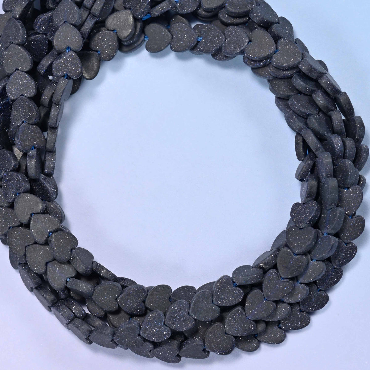 Matte Blue Sandstone flat heart beads, close view of the coiled strands in near-black navy with a matte finish