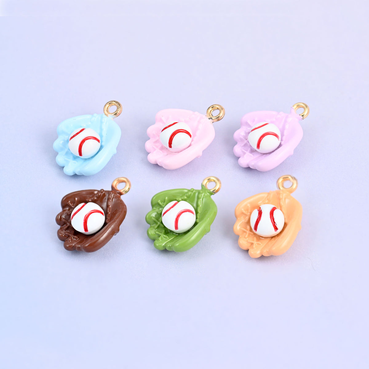 Six baseball charms scattered in a group, enamel gloves in brown, light orange, green, light blue, pink and light purple.