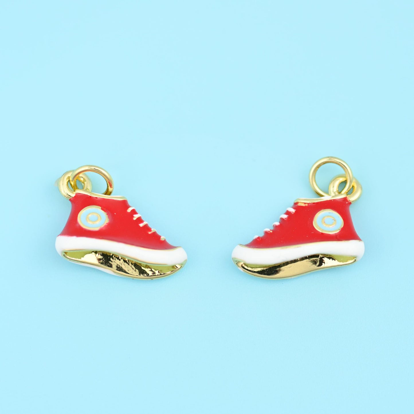 A miniature high-top in glossy enamel, laced in white with a small round patch at the ankle and a polished 18K gold filled…