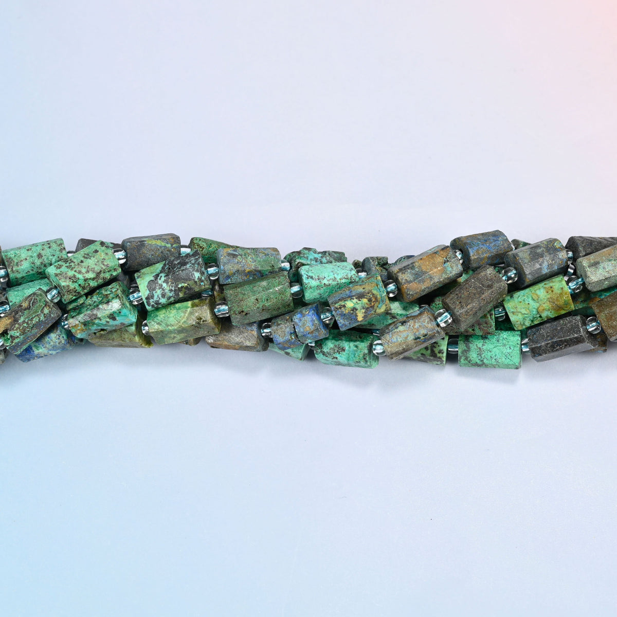 Strands of azurite chrysocolla faceted tube beads twisted together in a horizontal row