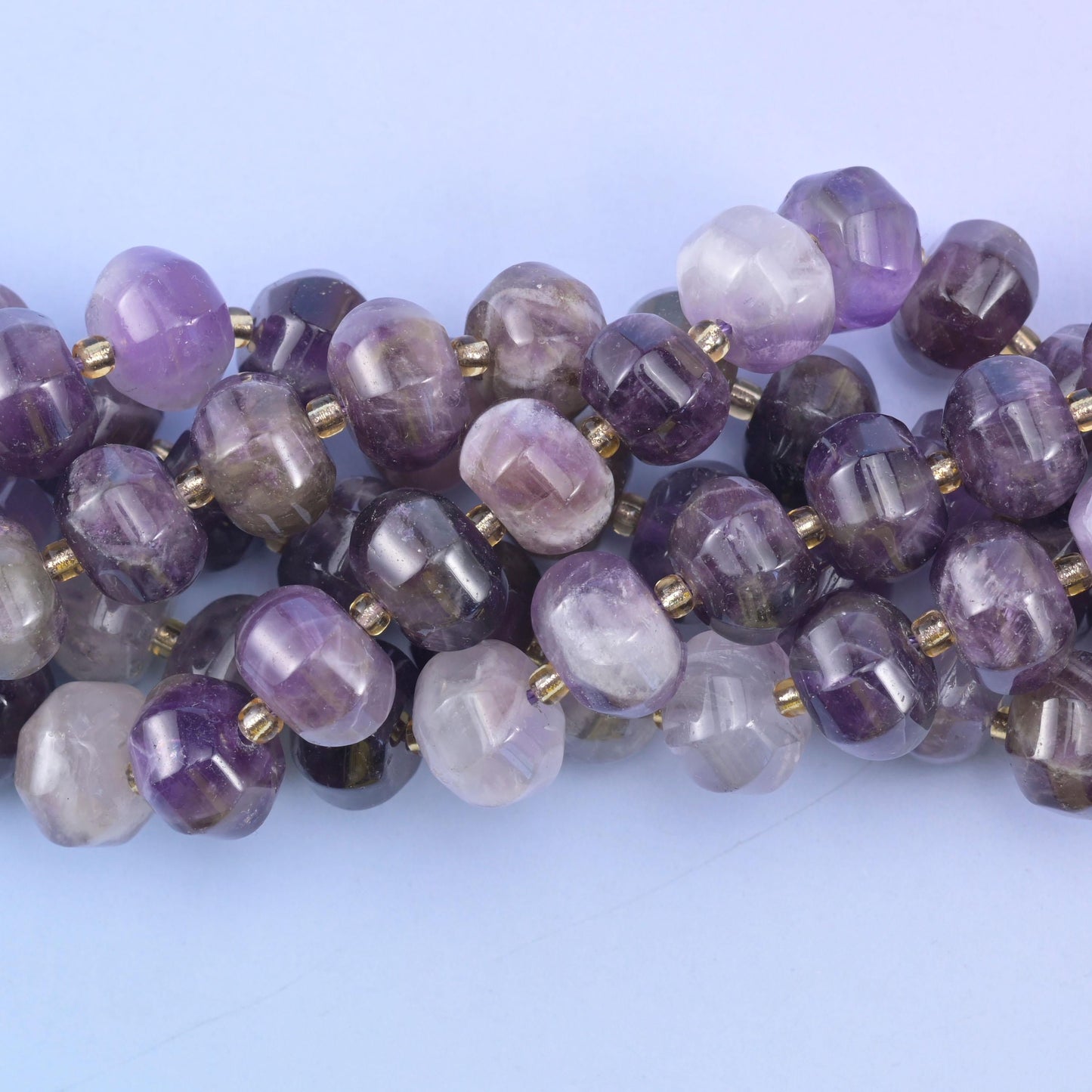 Macro shot where chevron bands of violet, grey and milky white run through a few overlapping beads