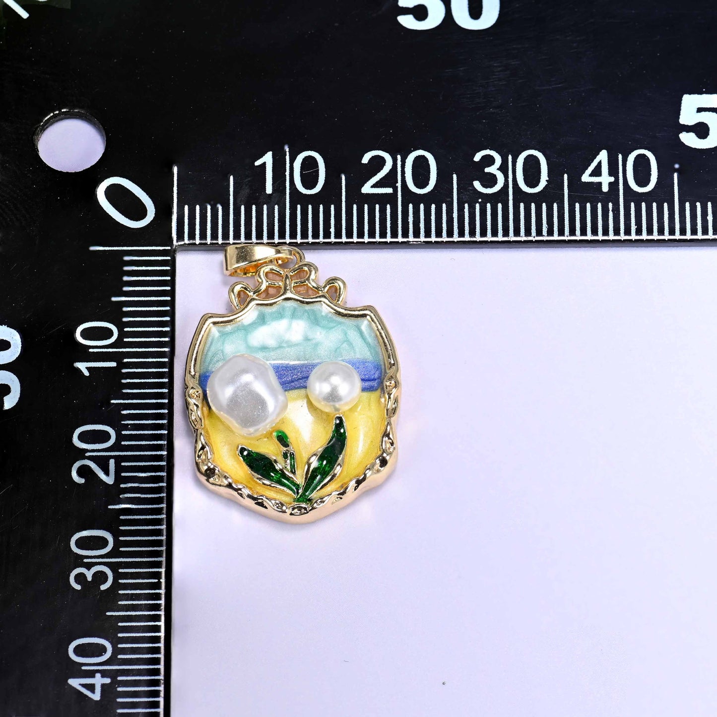 18K gold plated brass tulip charm pendant with a teal and yellow enamel garden scene, faux pearl tulip blooms, and green leaf details in an ornate shield frame.