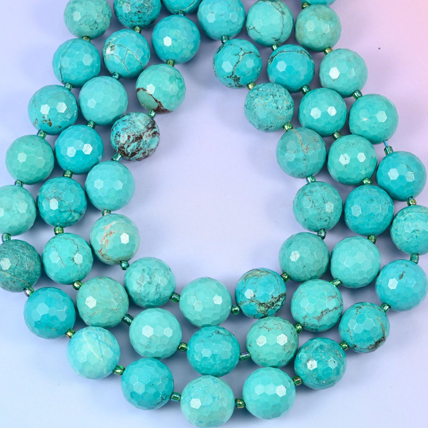 Big sea green to turquoise blue rounds webbed with fine brown and charcoal matrix, cut with dozens of shallow facets that dull the surface to a soft chalky sheen.