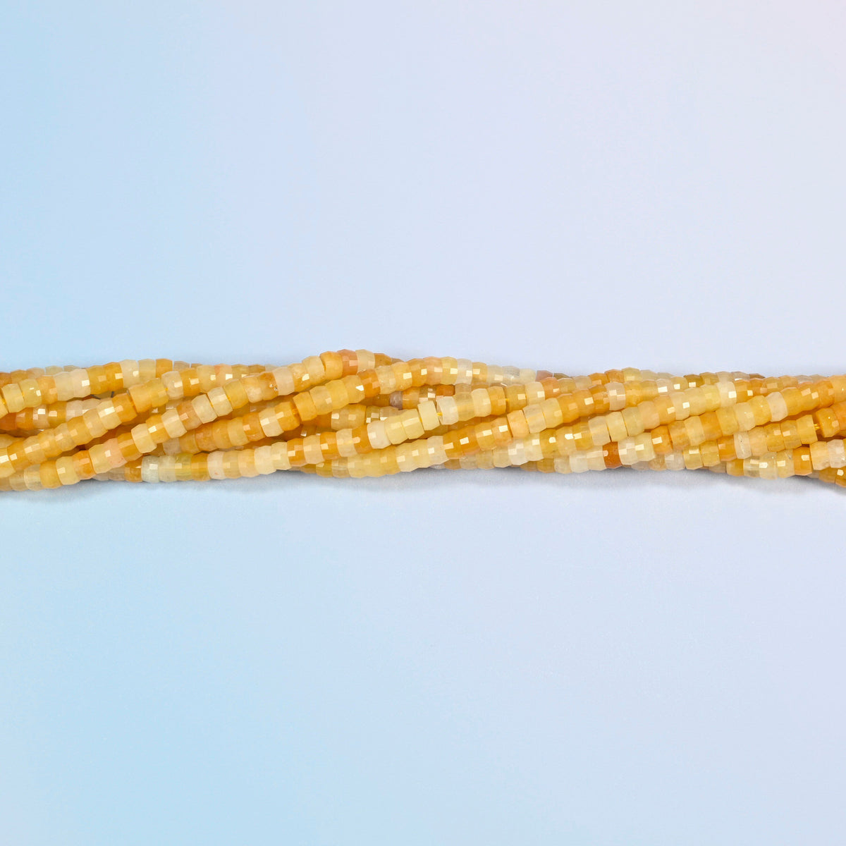 Strands of Gold Silk Jade faceted heishi disc beads twisted together in a horizontal row