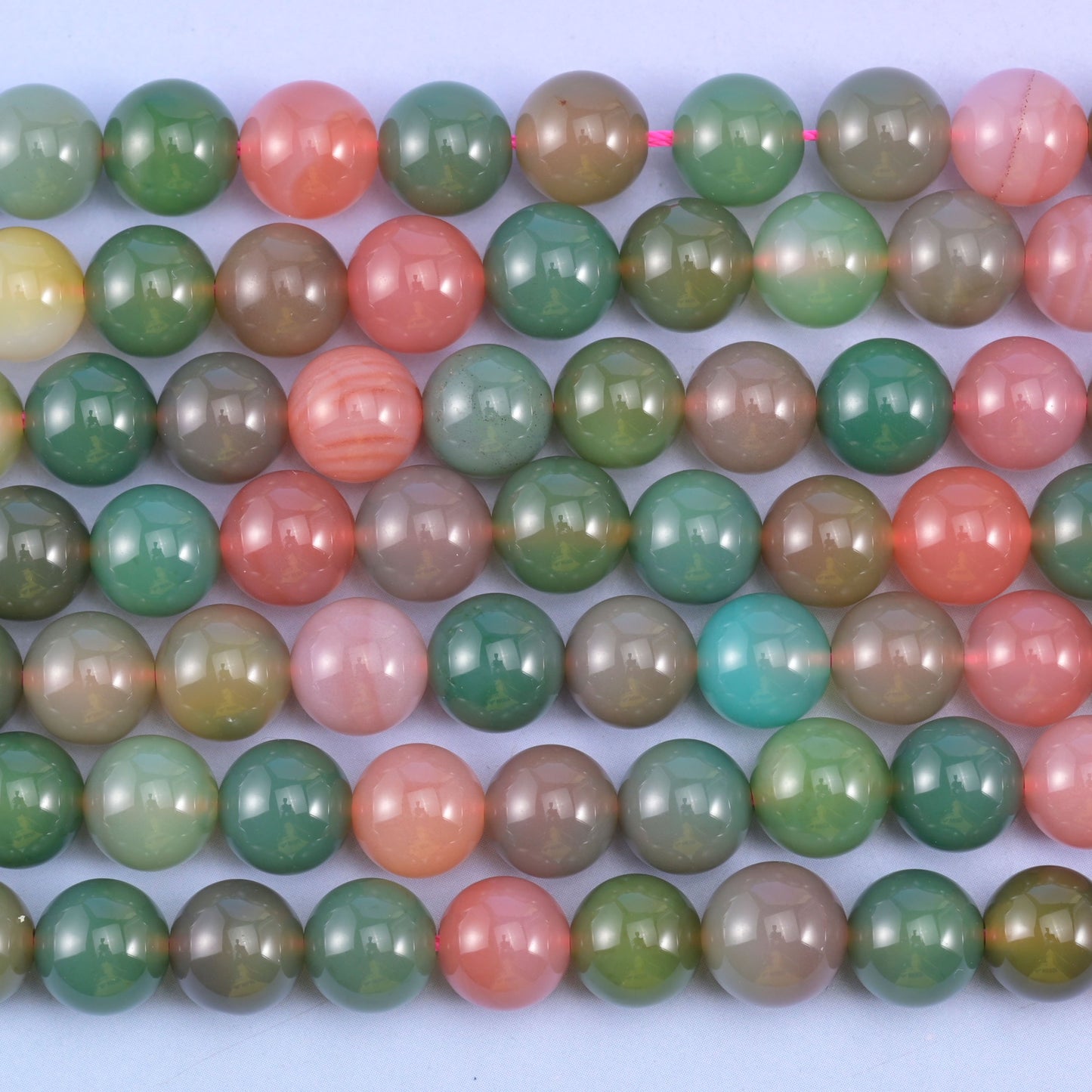 Green Yanyuan Agate smooth round beads in close parallel rows, colour proportion changing along each 14 inch strand