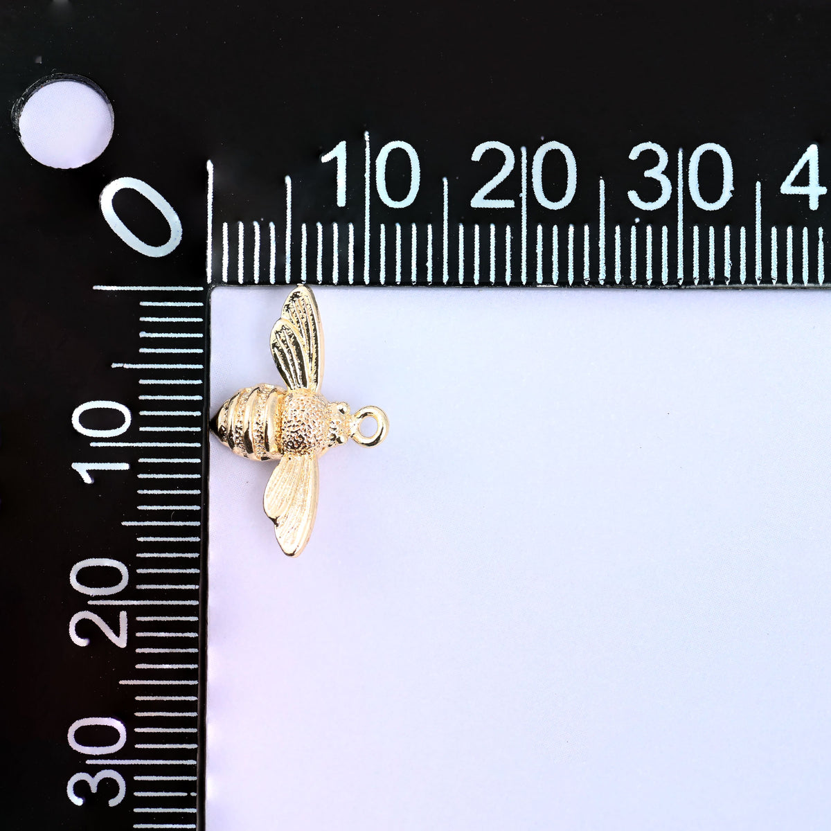 Small gold charms bee on a millimeter ruler showing the 11.7mm body height