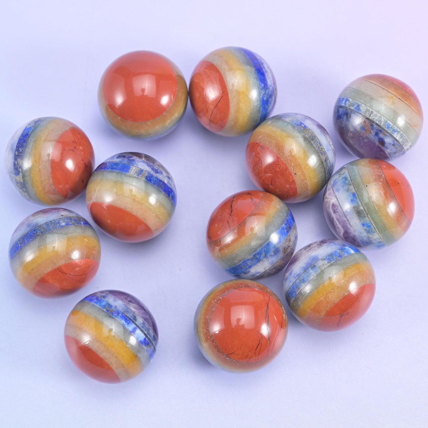 Group of banded spheres in mixed sizes scattered on lilac, every one carrying its own stripe pattern