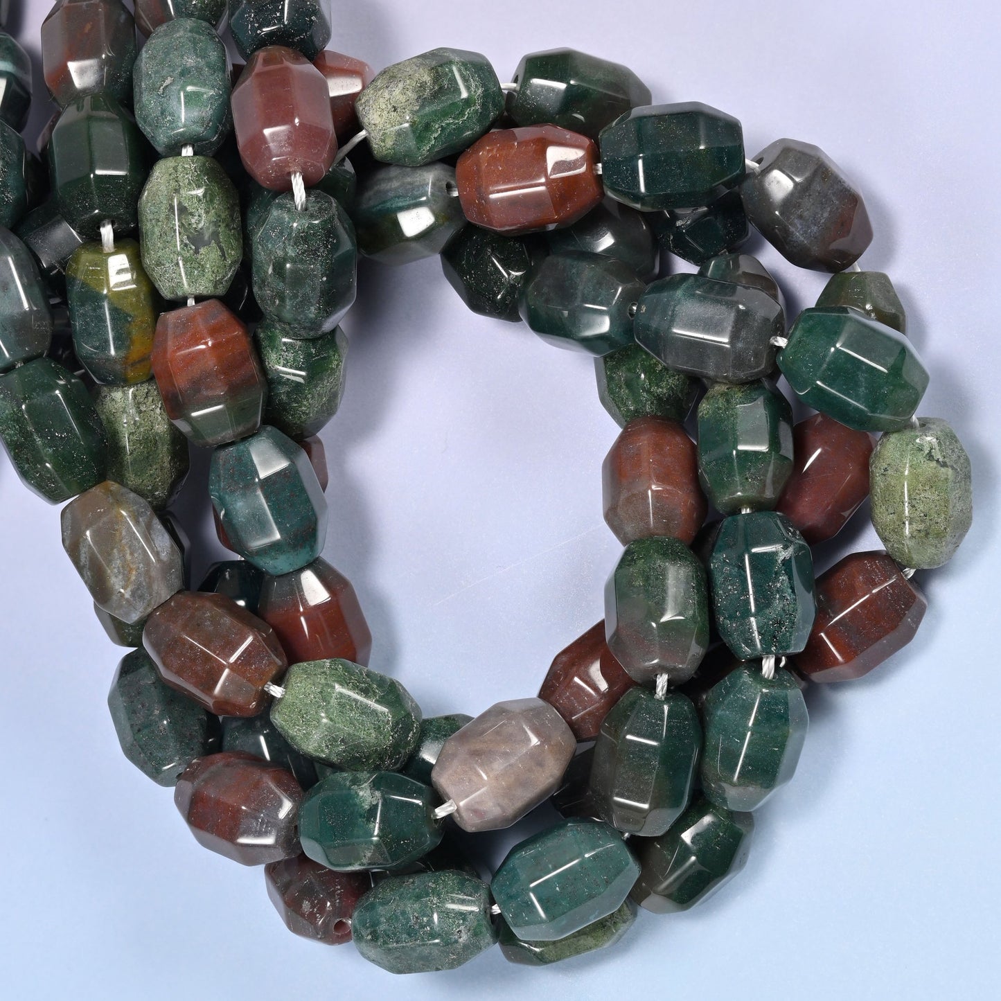 Wide circular coil of Indian Agate faceted barrel beads on a lavender and pink gradient background, showing the full wreath.