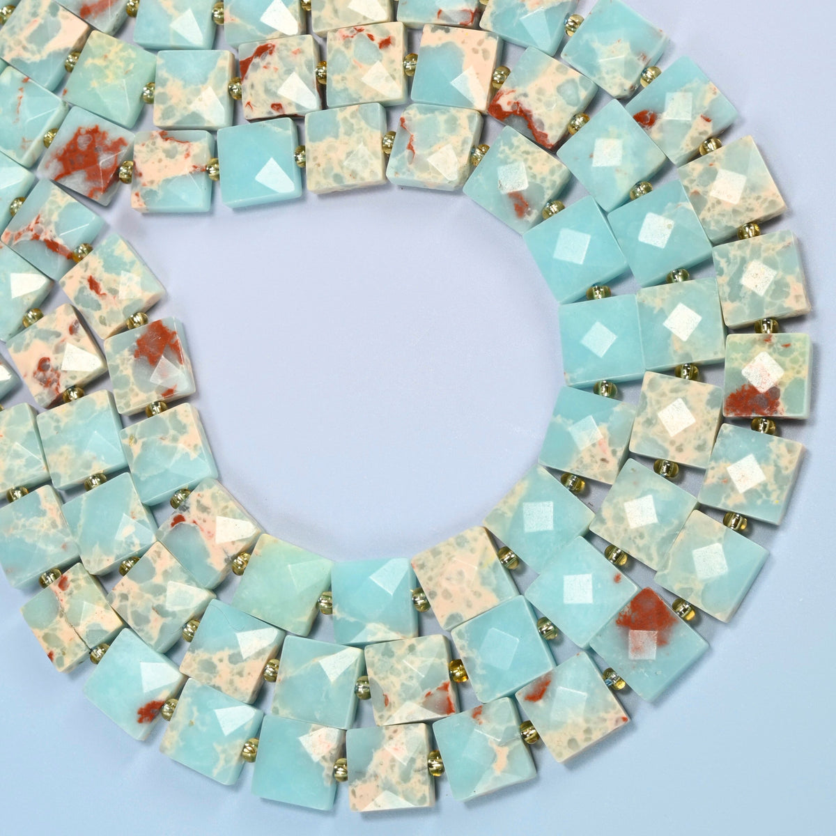 Dyed blue Shoushan stone faceted flat square beads curved into an open loop, light blue beads with cream and red-brown matrix
