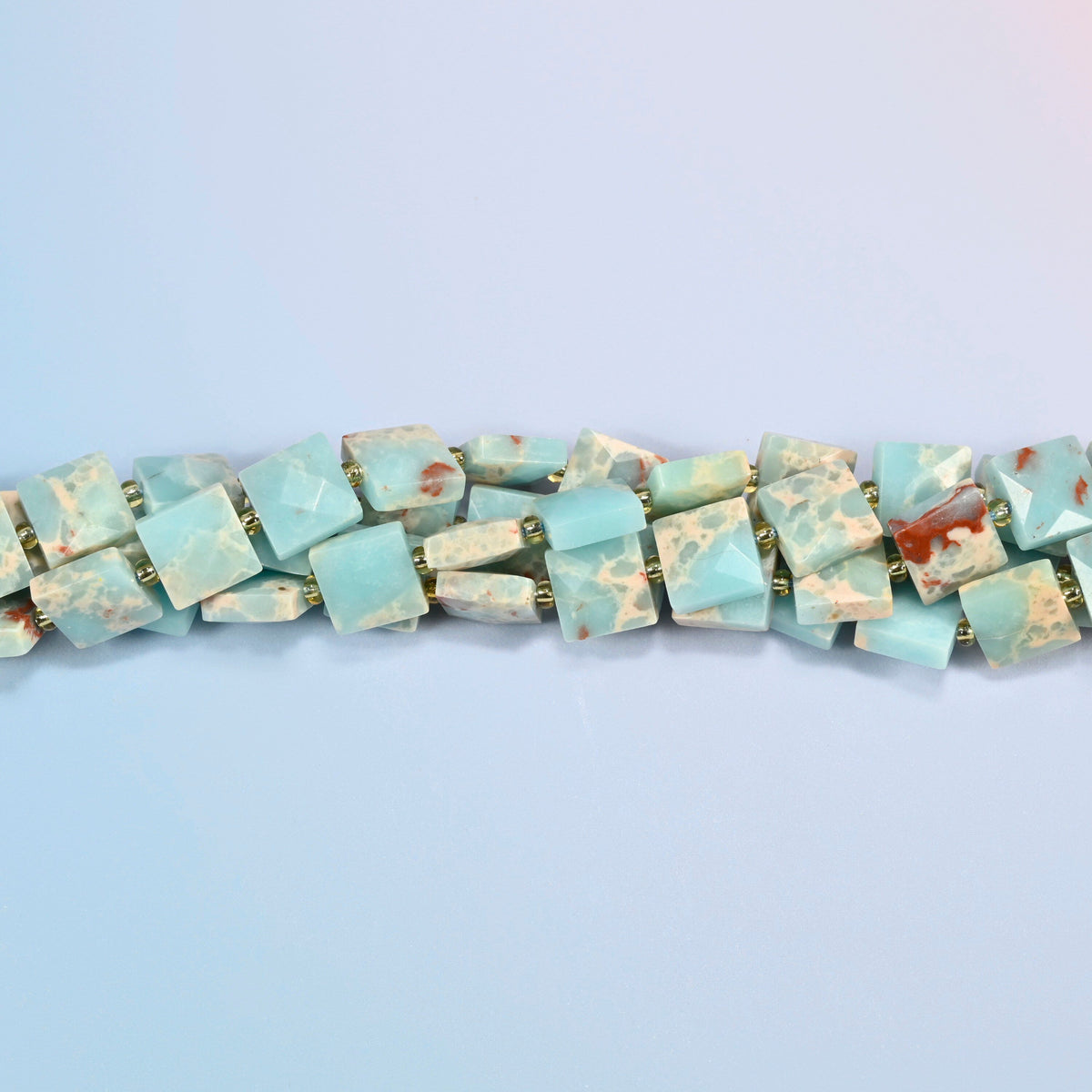 Strands of dyed blue Shoushan stone faceted flat square beads twisted together in a horizontal row