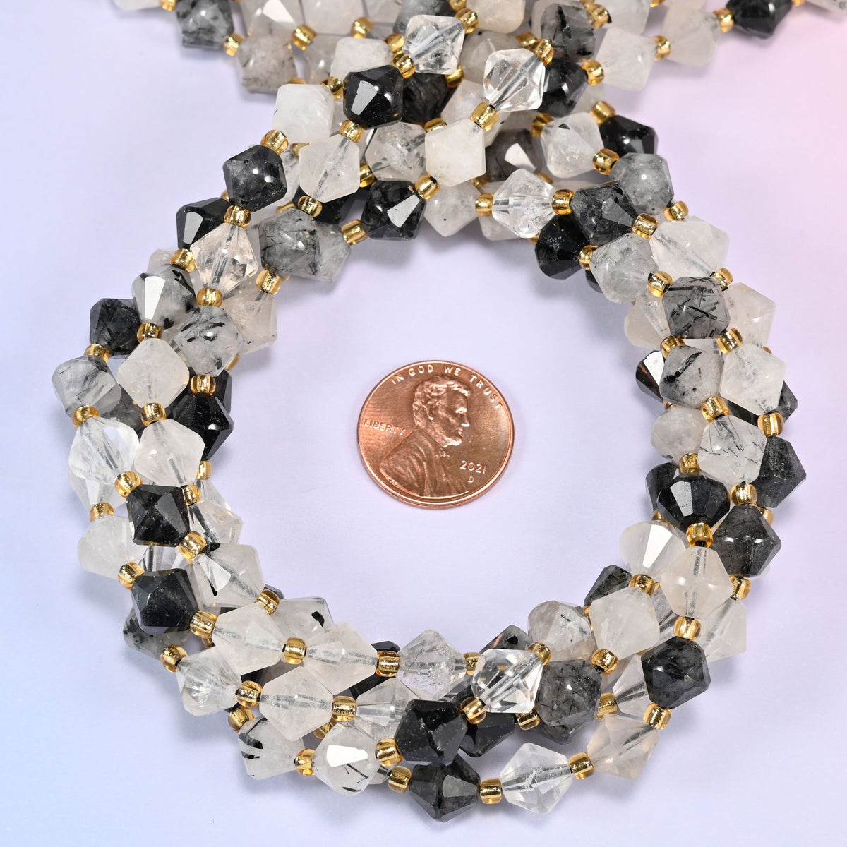 Black rutilated quartz bicone beads coiled into a round ring, 8mm beads with gold-tone spacers throughout.
