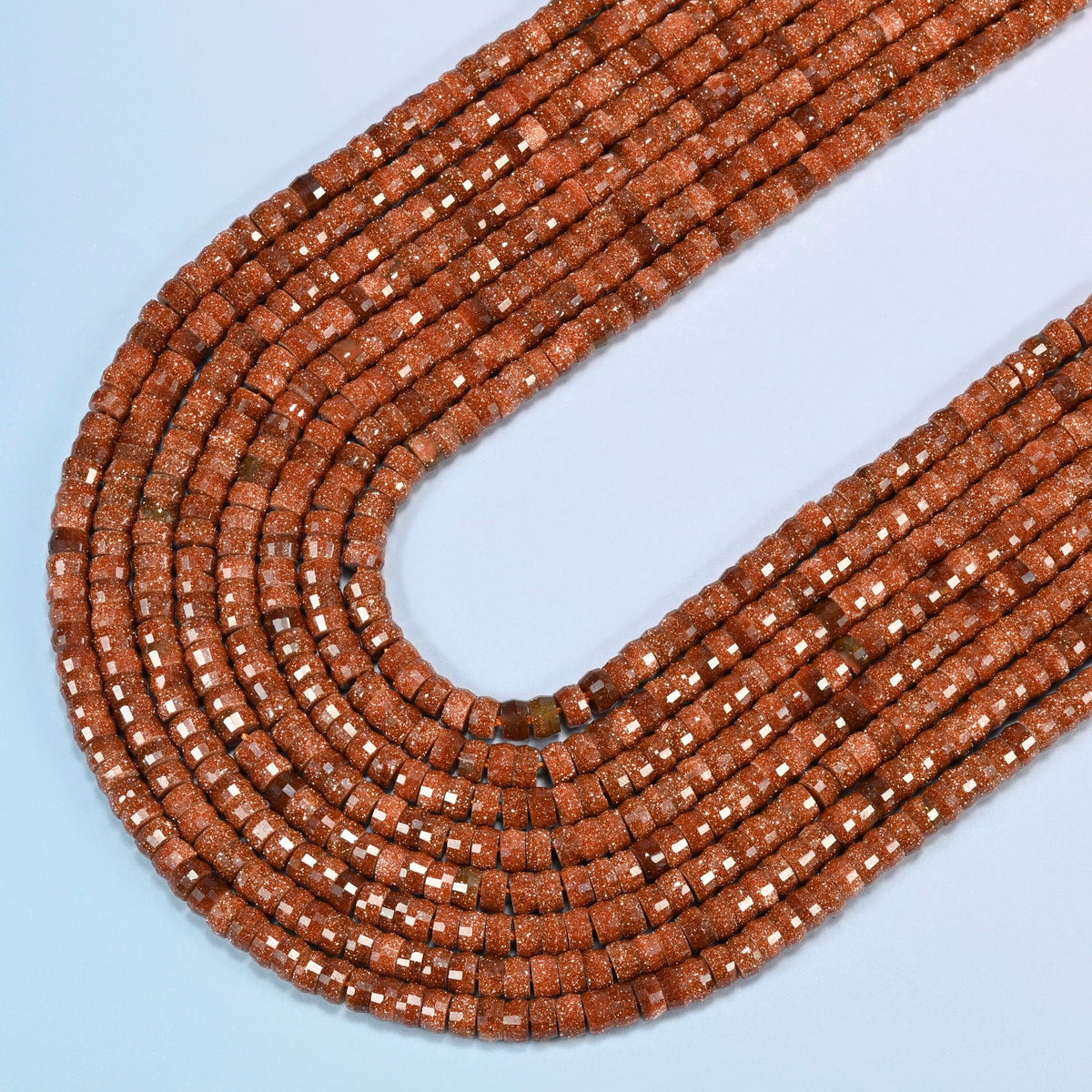 Gold sandstone faceted heishi disc beads in several strands curved into a wide U, copper brown glass with fine gold glitter