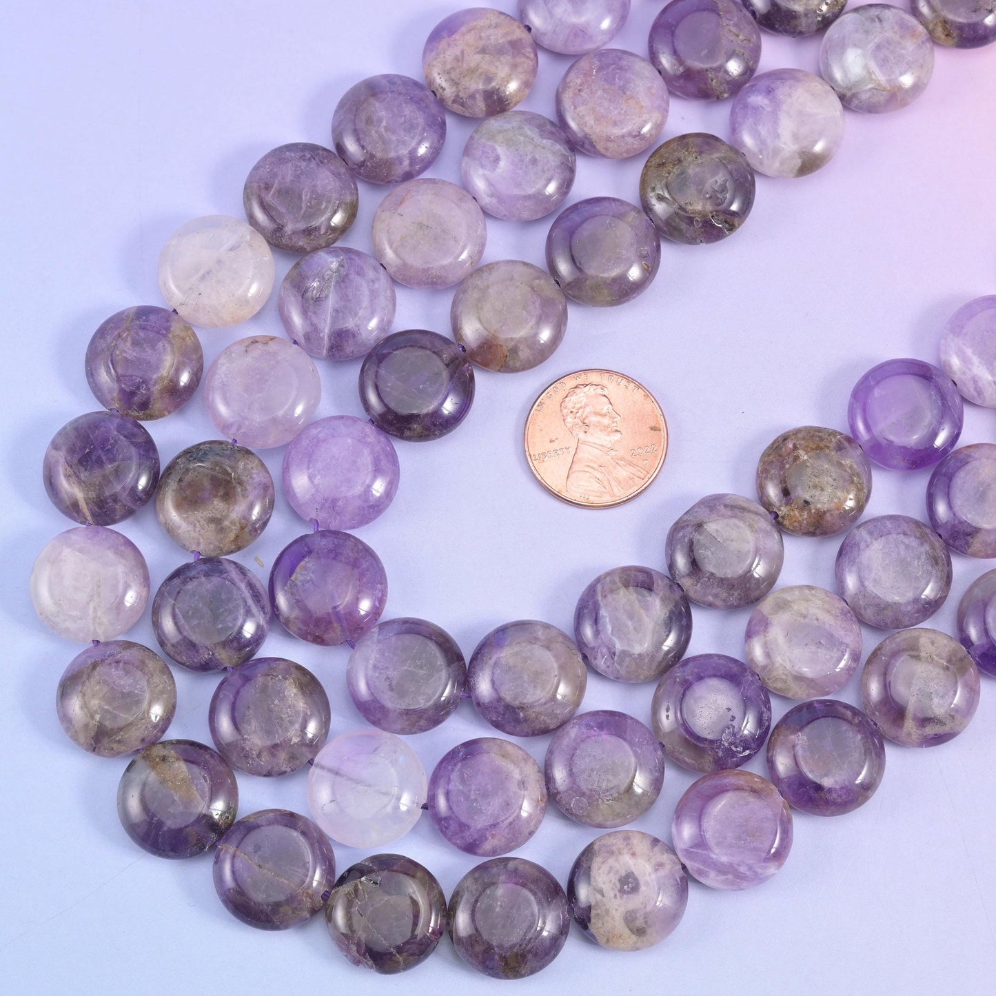 Amethyst coin beads arranged around a US penny for size comparison