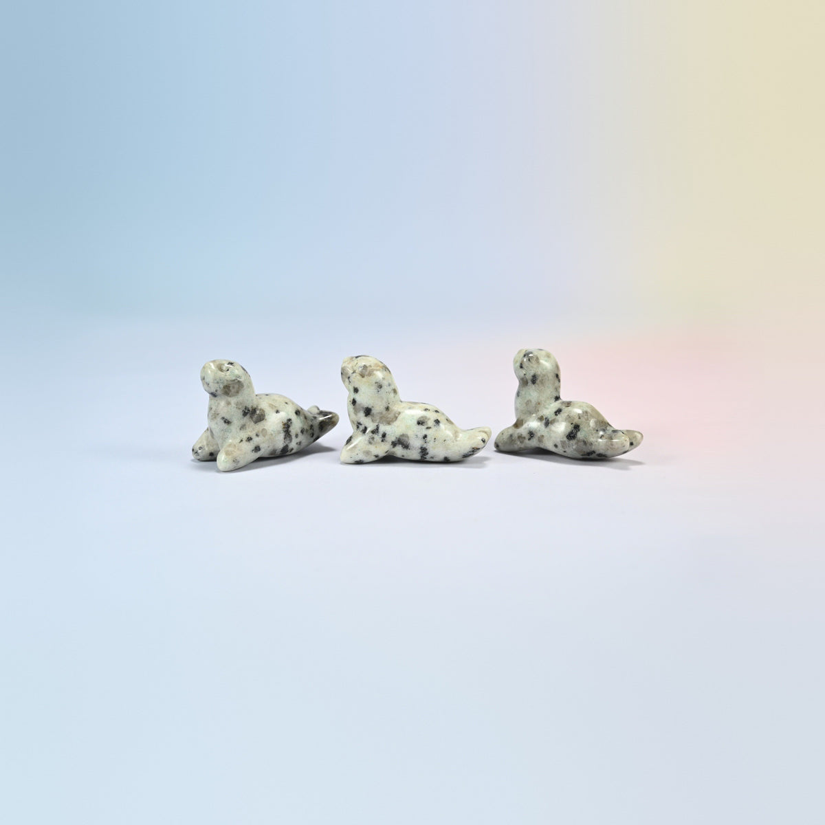 Three kiwi jasper sea lion crystal carvings, 1.5 inch, cream natural stone with black spots