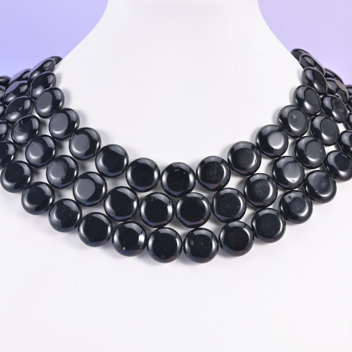 Black obsidian 15mm coins layered on a white display bust, four rows overlapping like a collar necklace