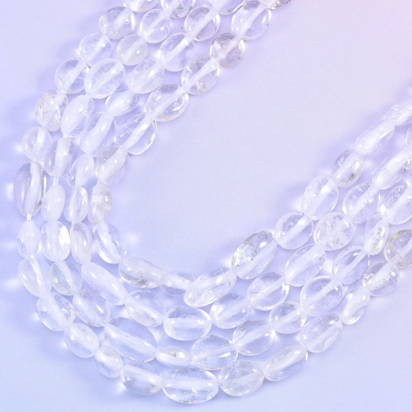 Strands curving into a soft V, colourless beads picking up the lilac background