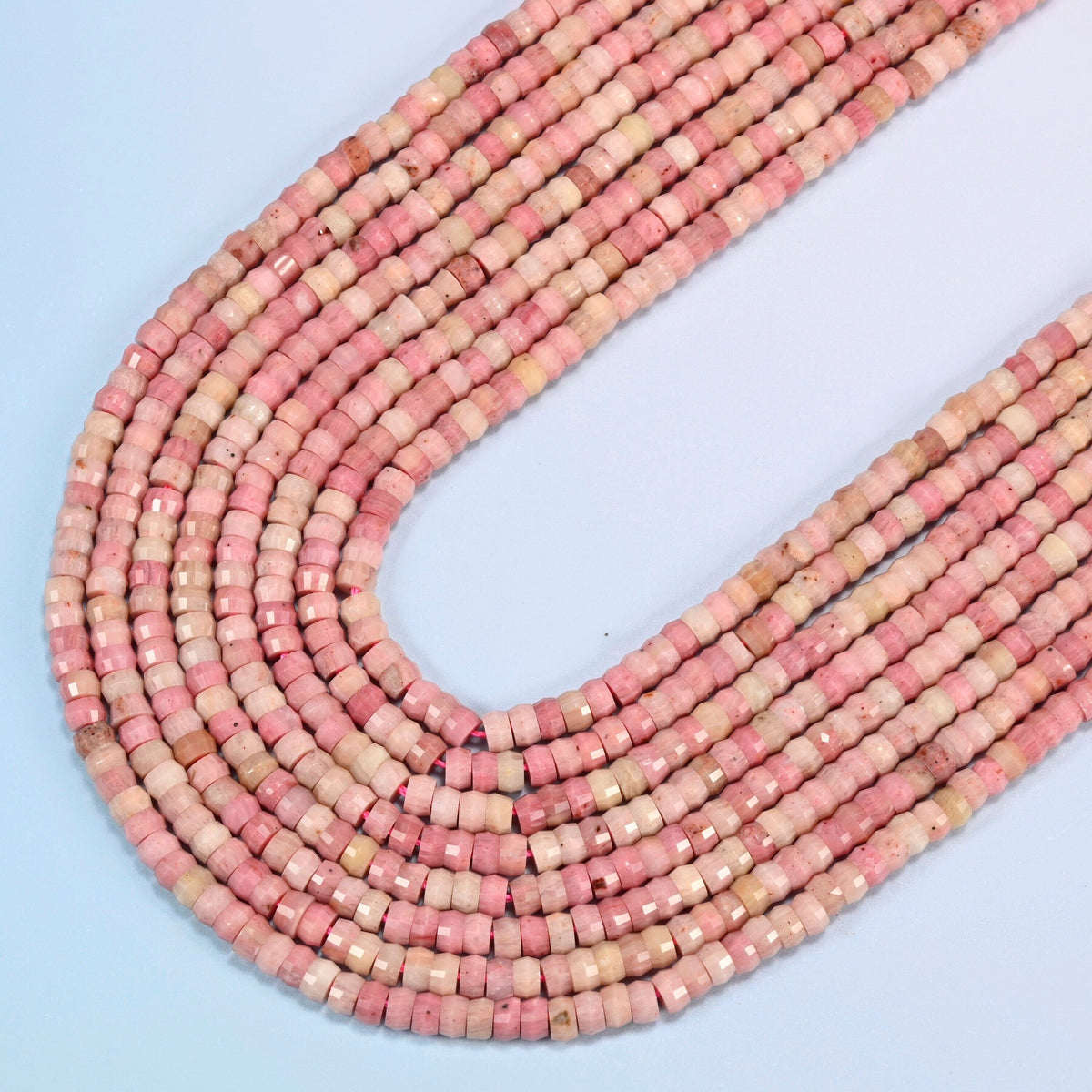 Pink rhodonite faceted heishi disc beads in several strands curved into a wide U, light pink and rose stone