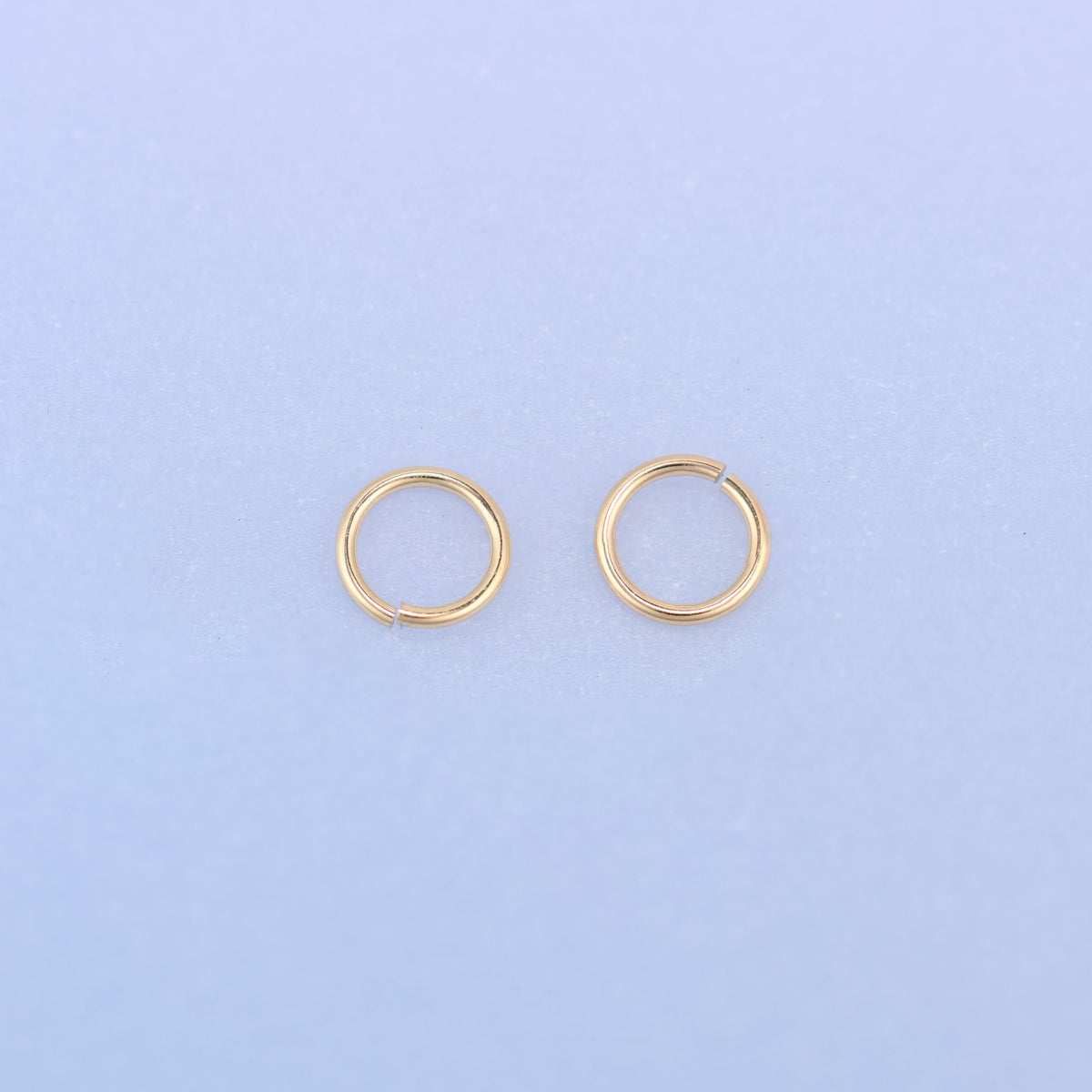 Two 14K gold filled open jump rings side by side, their cut ends facing each other, showing how cleanly the 22 gauge wire is finished.