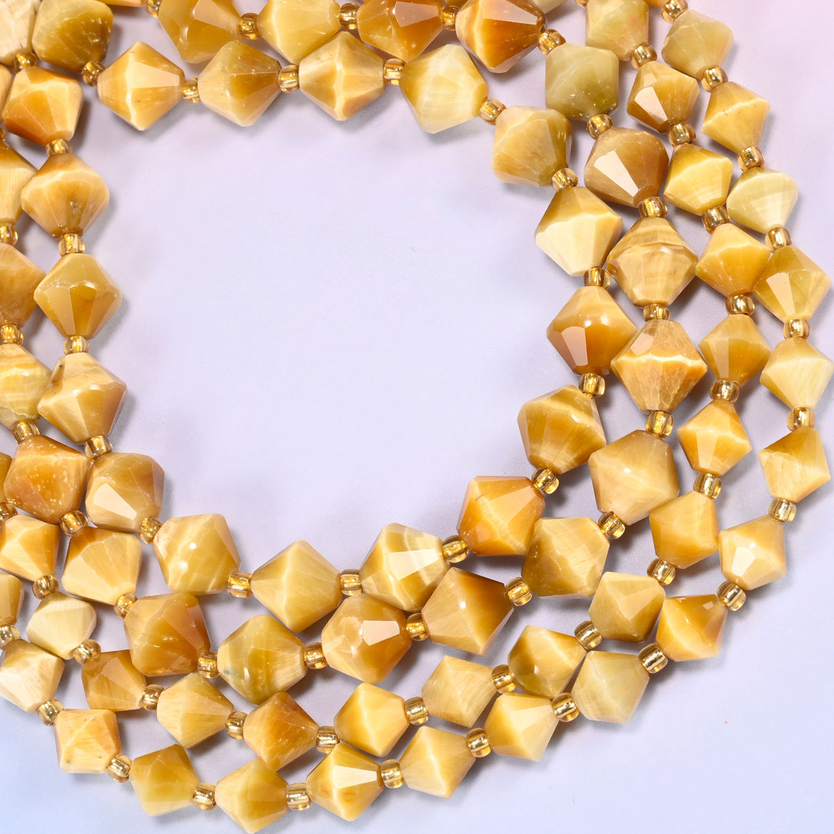 Gold tiger eye bicone beads formed into a wide open ring, the chatoyant sheen catching along the ridge of each facet.