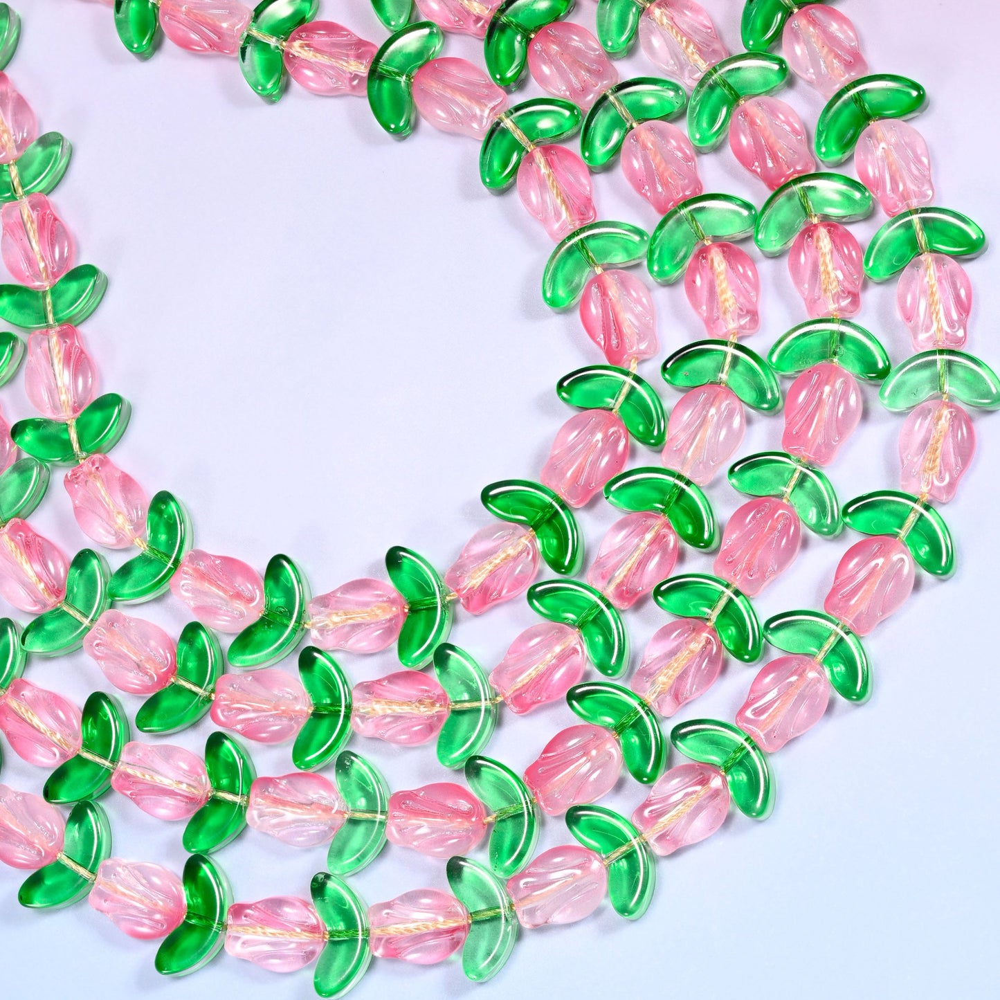 Circular coil of tulip and leaf glass bead strands forming a wreath shape on a lavender background.