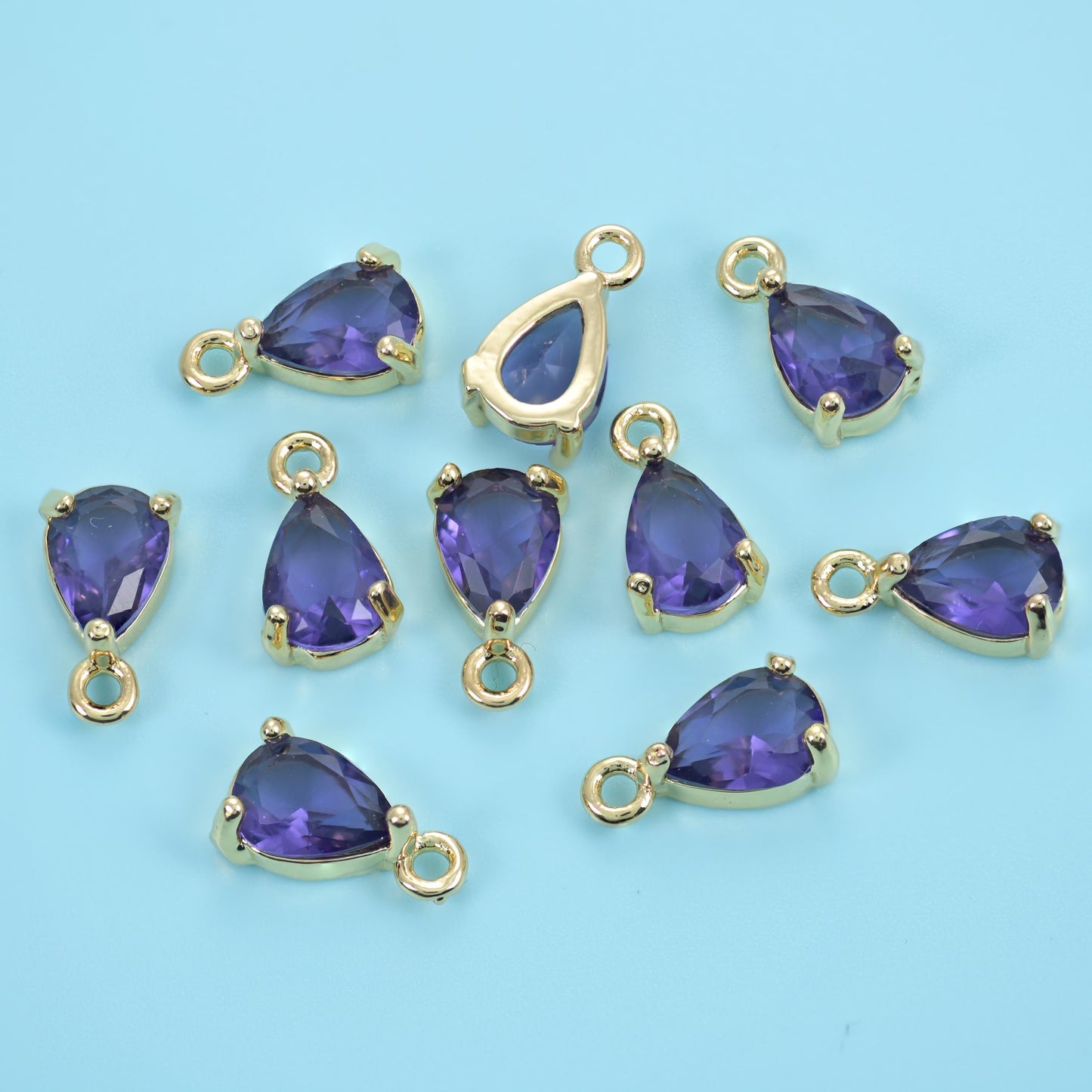 A pear-cut zircon held in a slim gold prong setting with a ring at the point, faceted right through so light passes clean…
