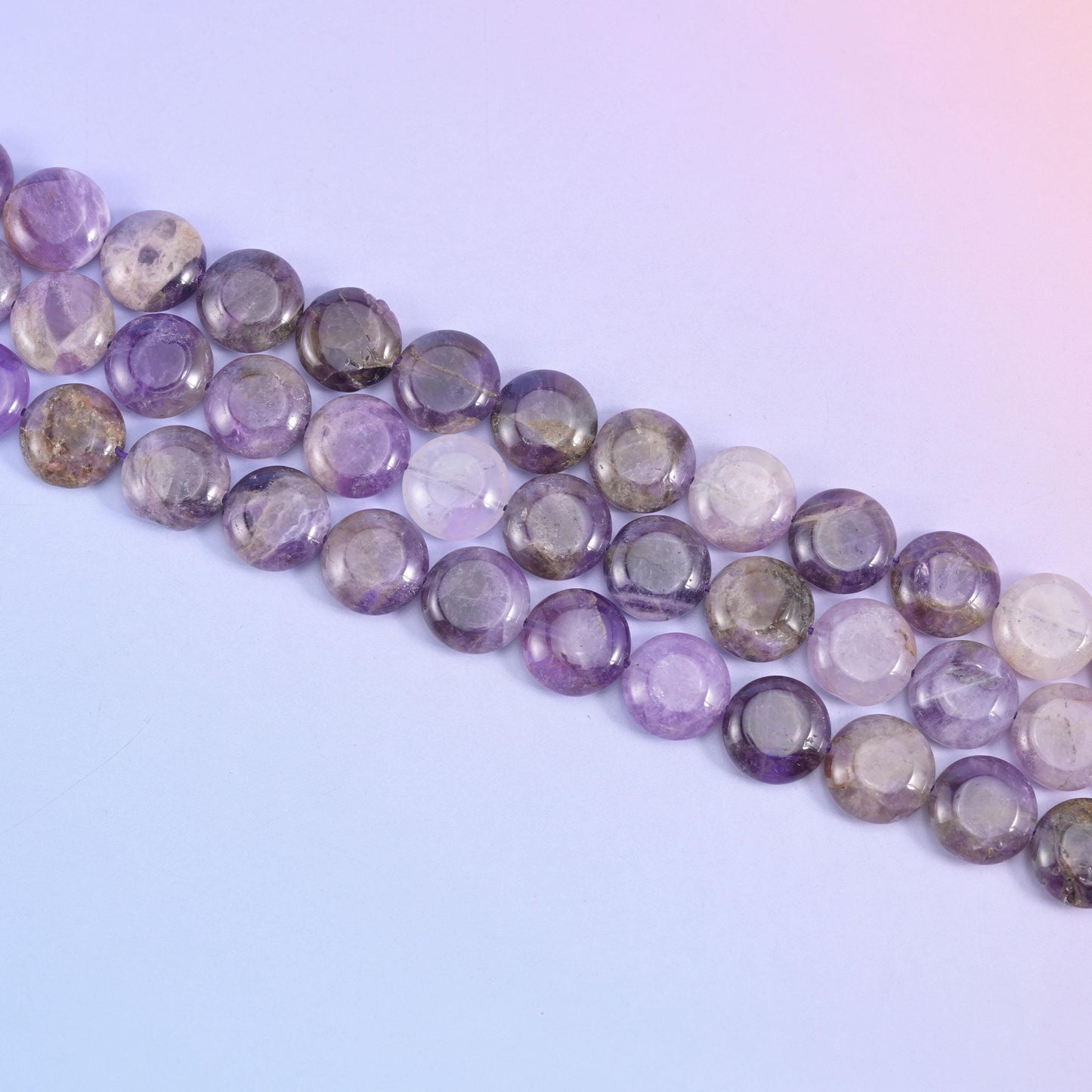 Diagonal run of 15mm Amethyst coins across a soft blue background
