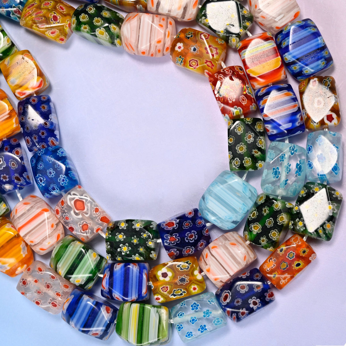 Millefiori cuboid beads with the corners cut into flat facets.