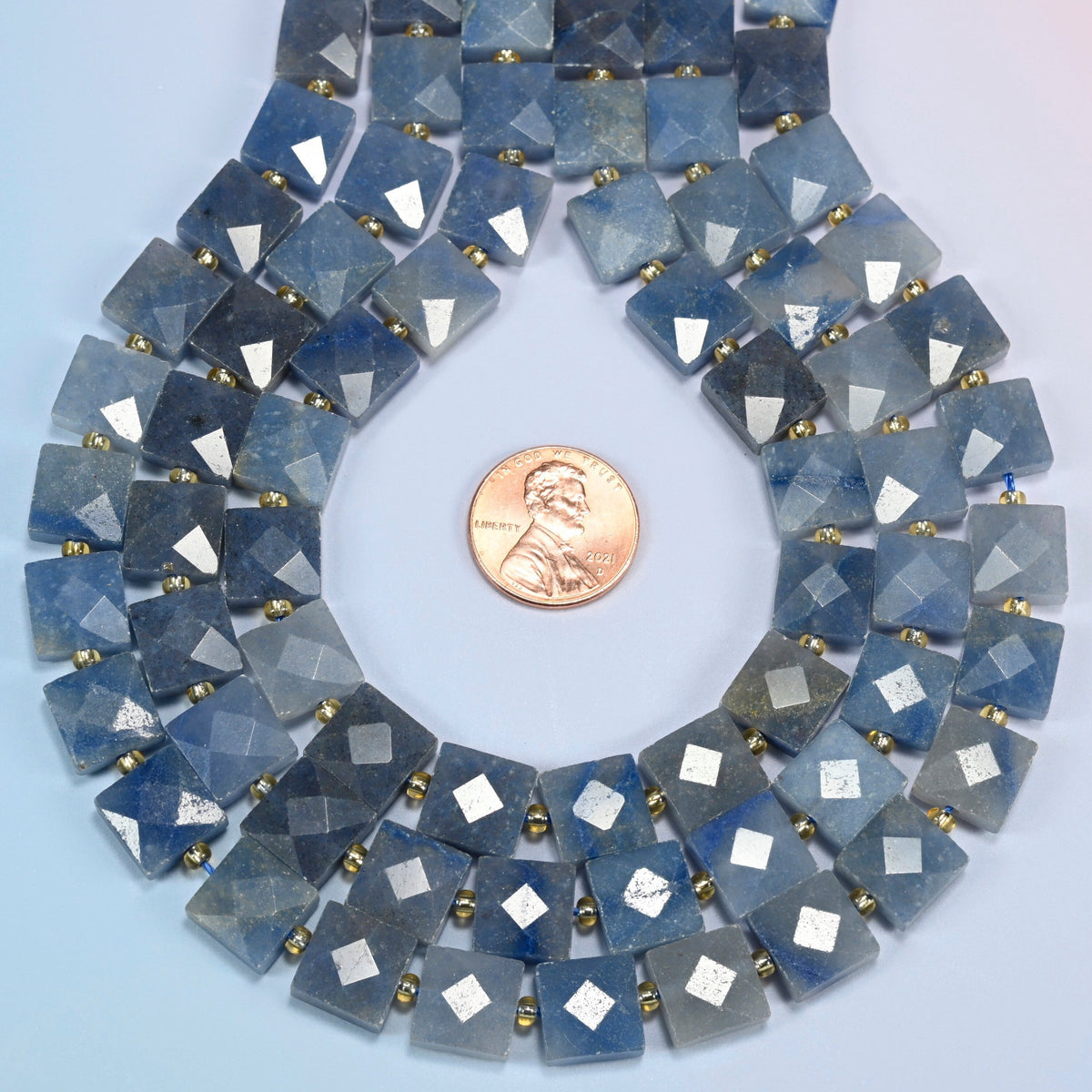 Natural blue aventurine faceted flat square strands formed into a teardrop loop around a US penny for scale
