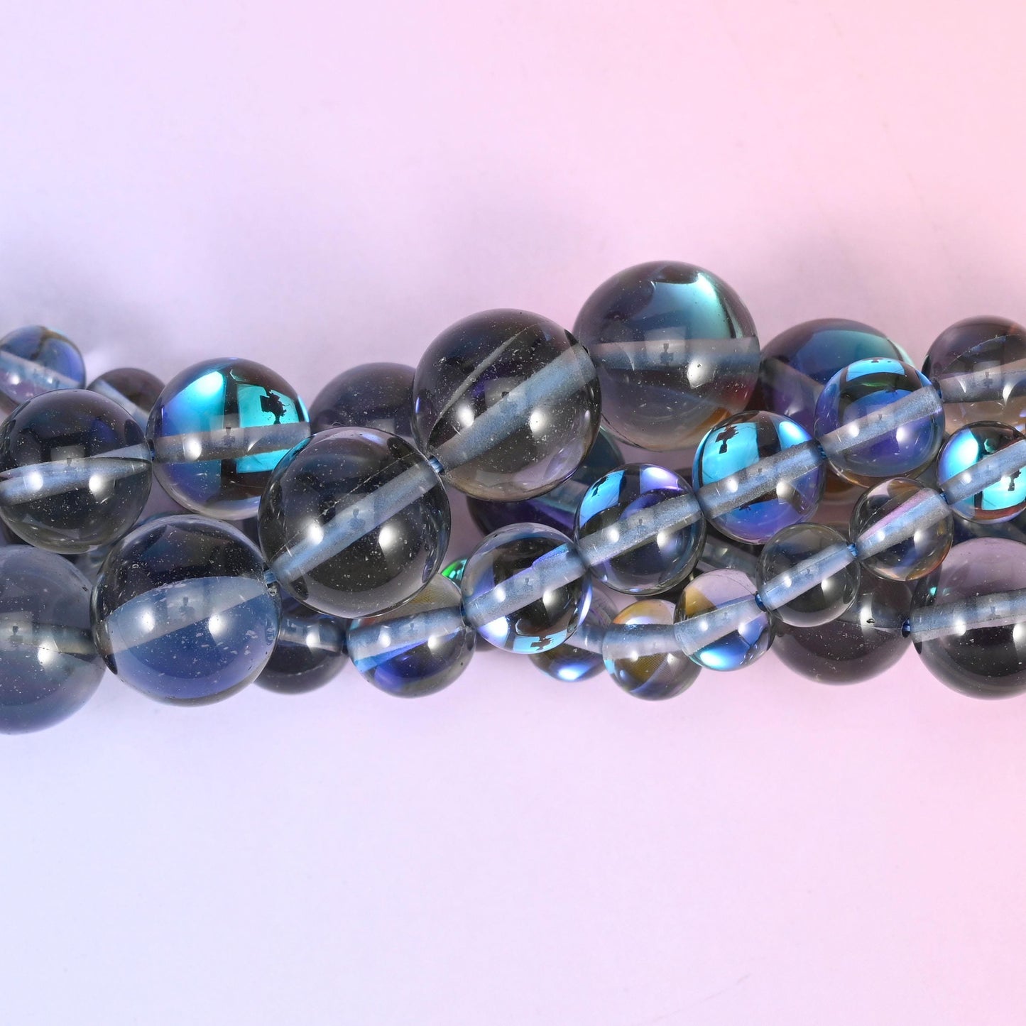 Smoky grey glass rounds with a high glossy polish lit by a strong peacock flash of blue, green and violet