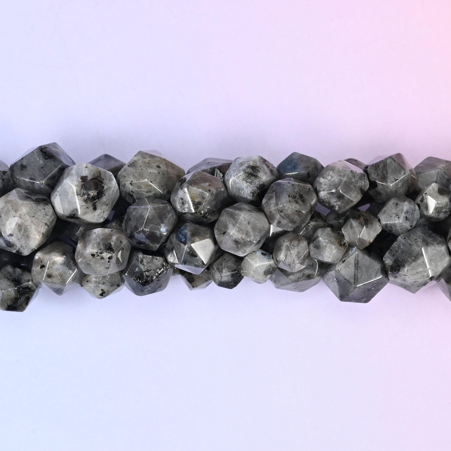 Smoky charcoal grey speckled with black and lit by a cool silvery flash across the cut faces, each bead shaped into a many-sided star so the sheen jumps from facet to facet as the strand moves.