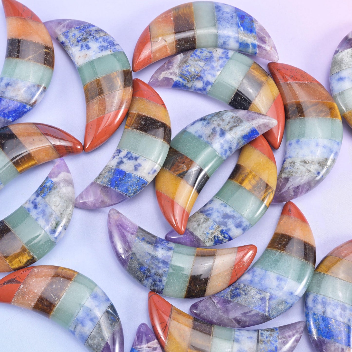 Crescent moon carvings in glossy banded stone, curved edges catching light beside rounded coin pieces