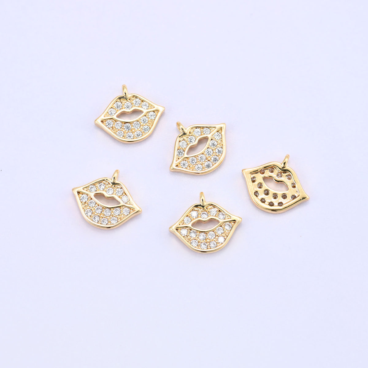 Small gold charms, five lip charms with one turned over to show the back