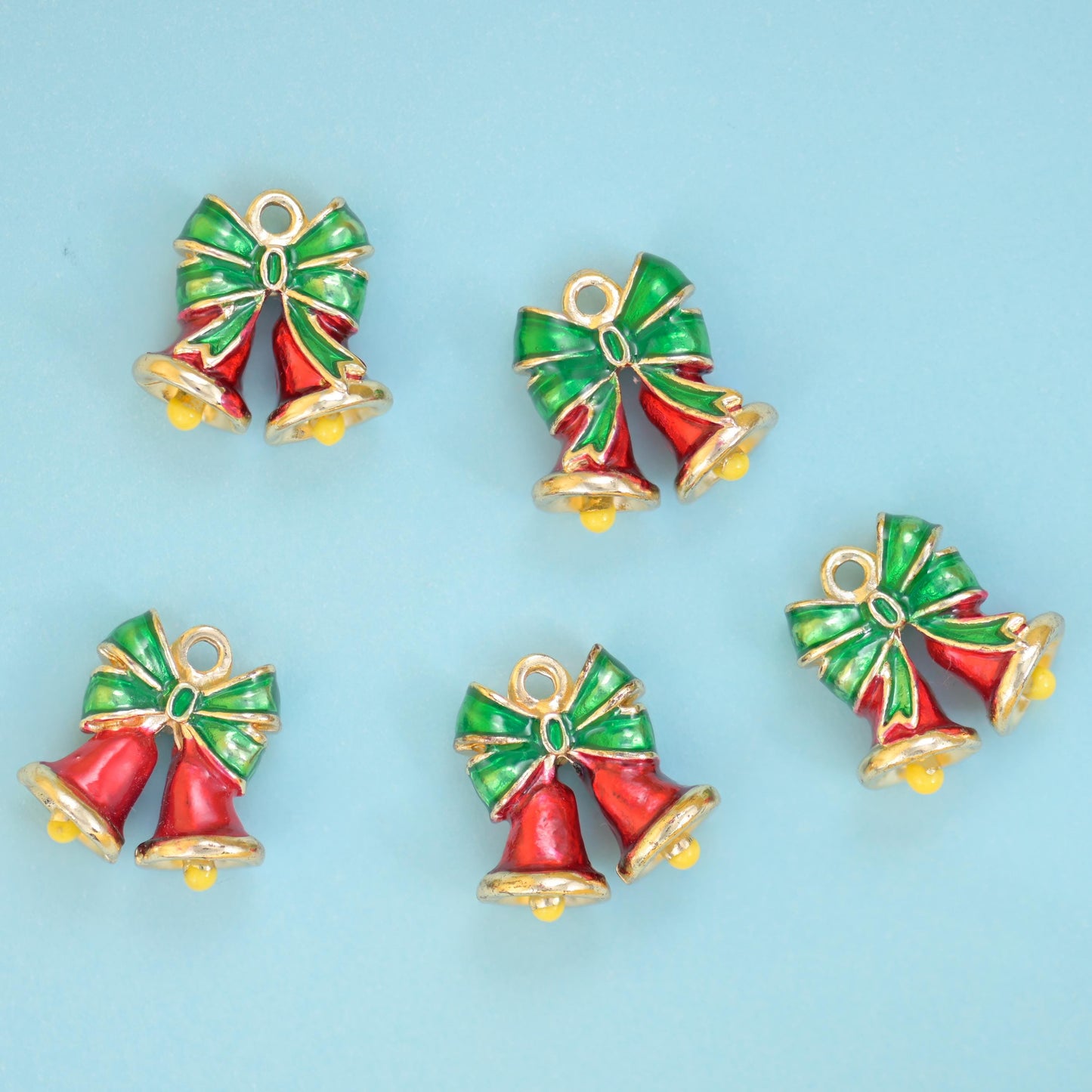 A pair of glossy red enamel bells tied with a bright green enamel bow, edged in warm 18K gold filled brass with tiny gold…