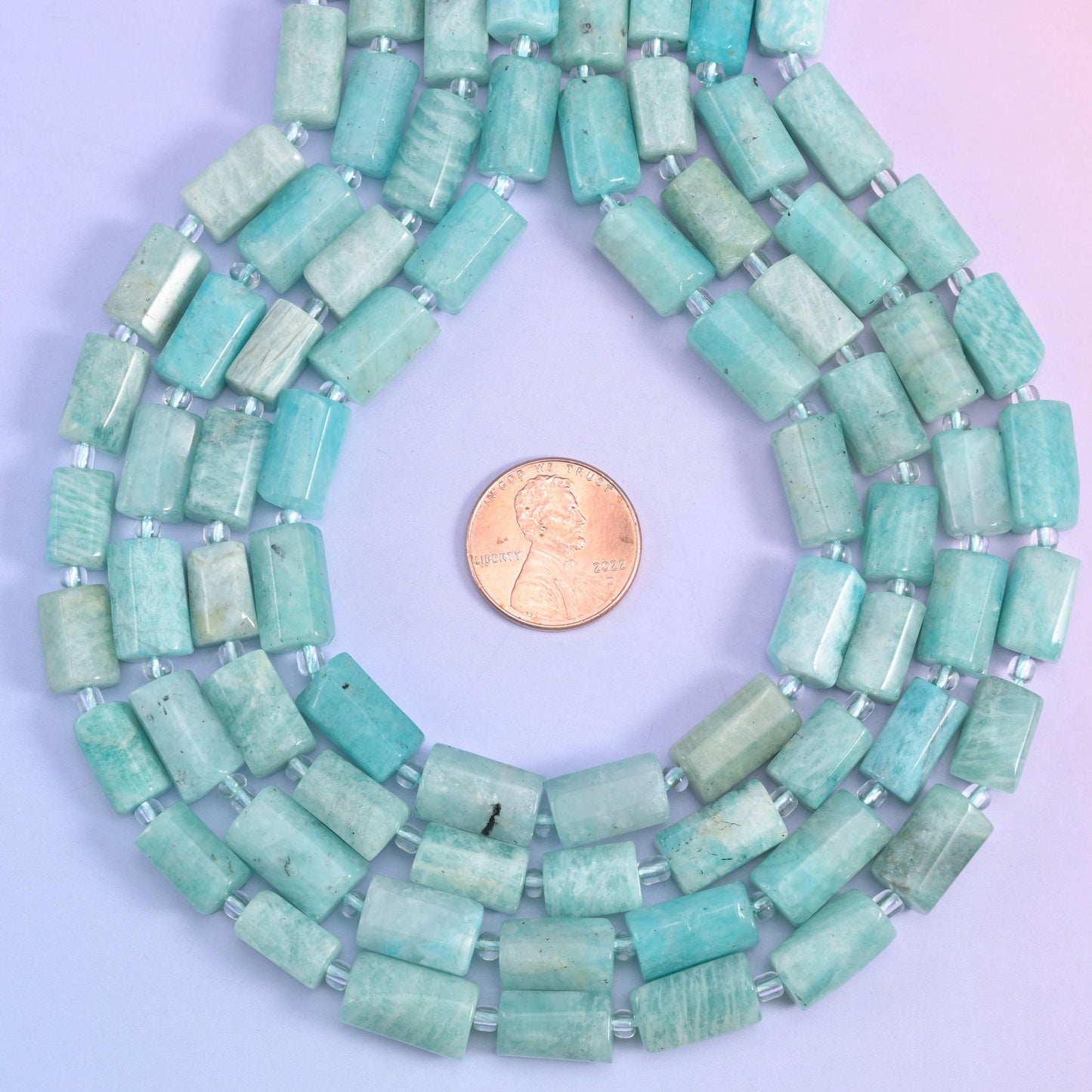 Coiled amazonite tube bead strands with a penny set at the centre for size comparison