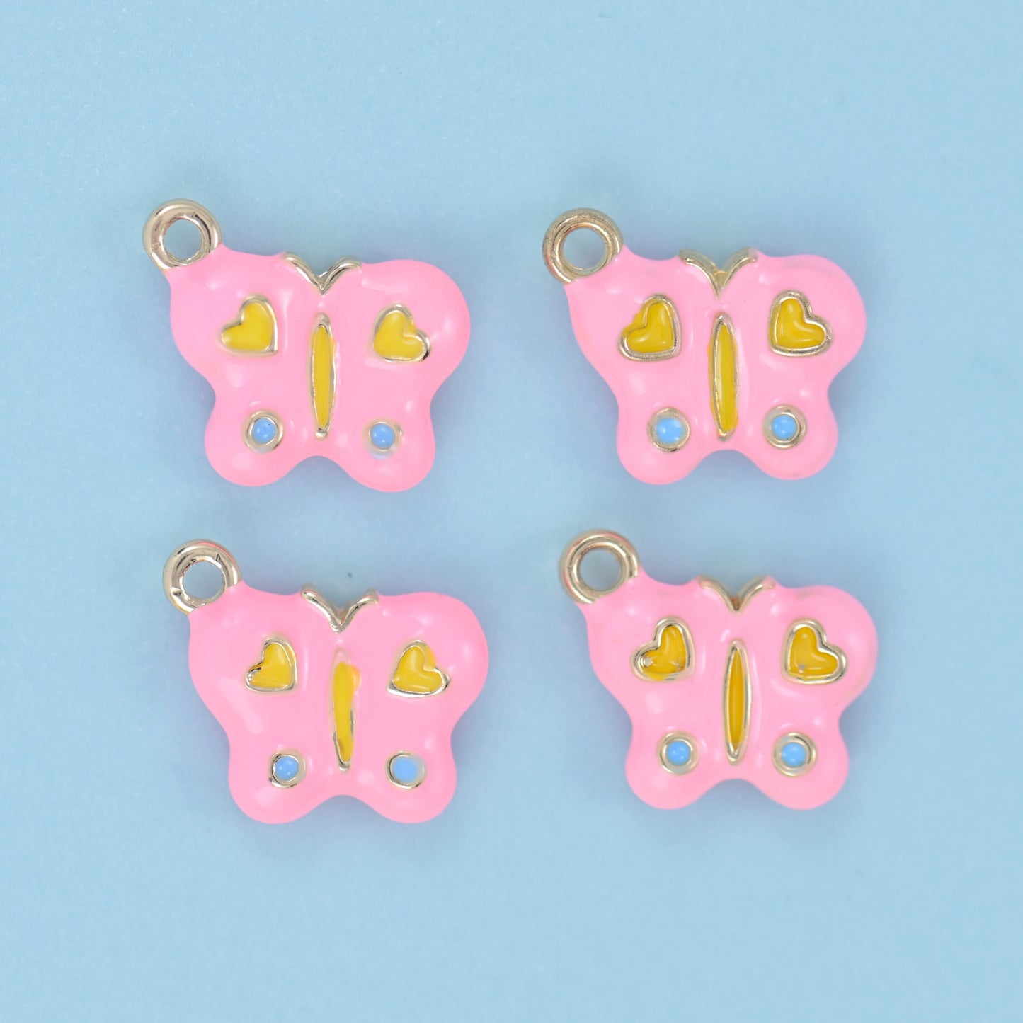 A rounded butterfly filled with soft pastel enamel, decorated with two little hearts on the upper wings