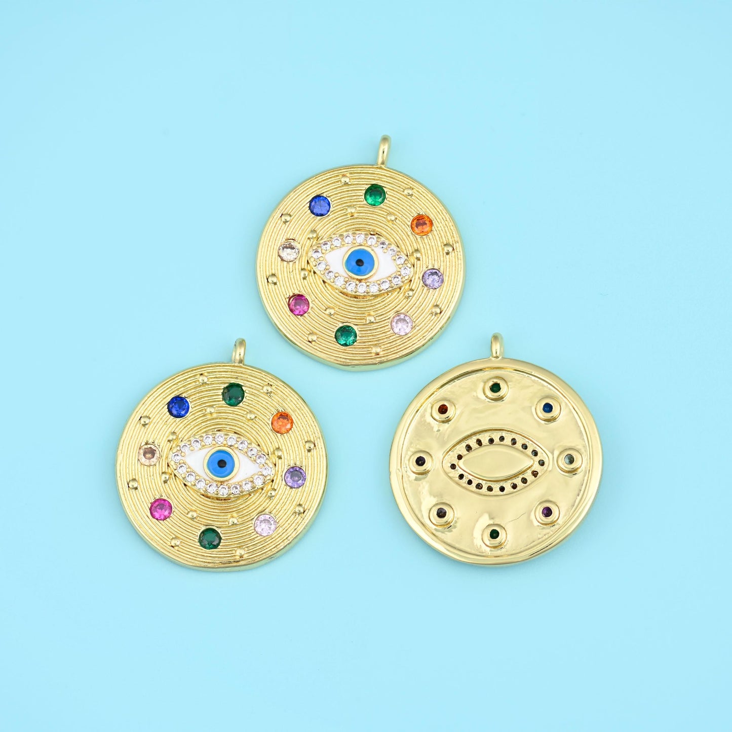 A large round medallion with a textured hammered face, an eye motif set at the centre in white and blue zircon